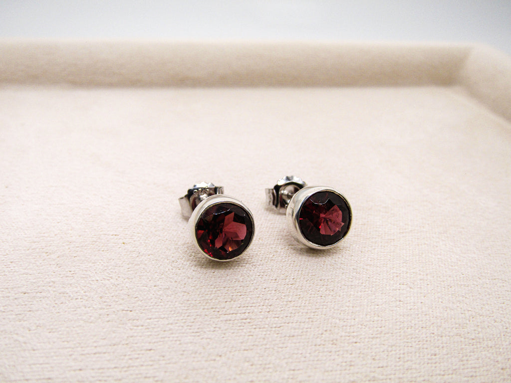 Pair of silver earrings with red gemstones on a white surface