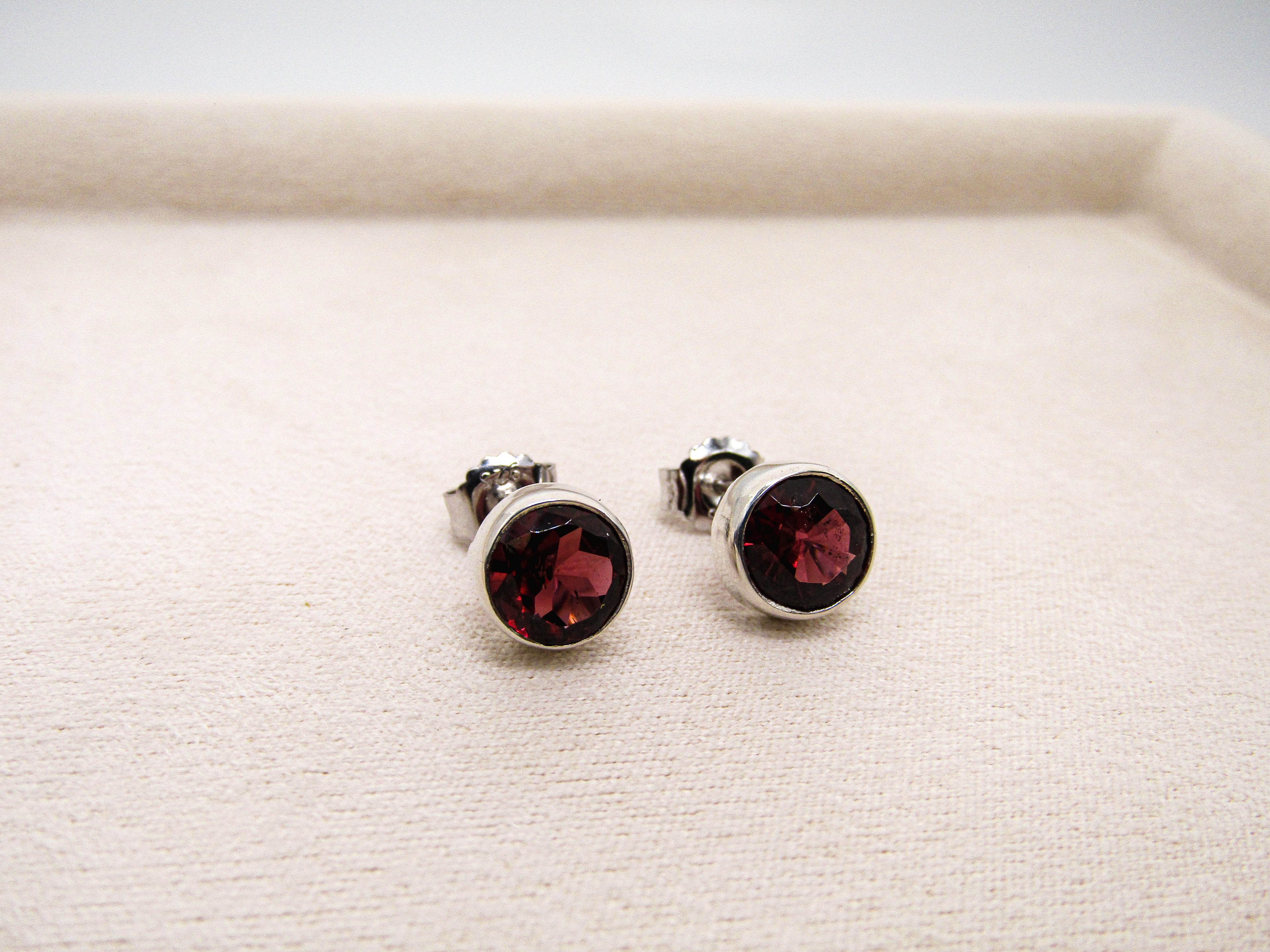 Pair of silver earrings with red gemstones on a white surface