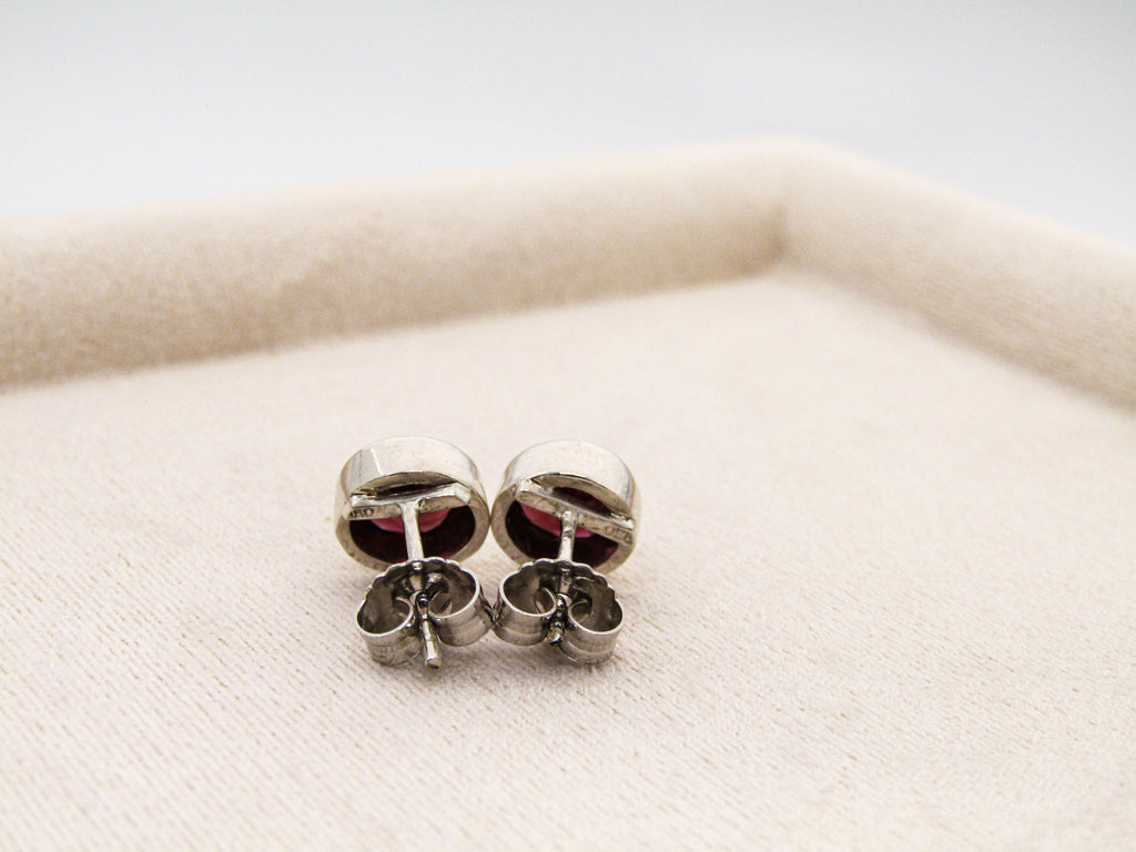 Silver earrings with red stones on a white surface