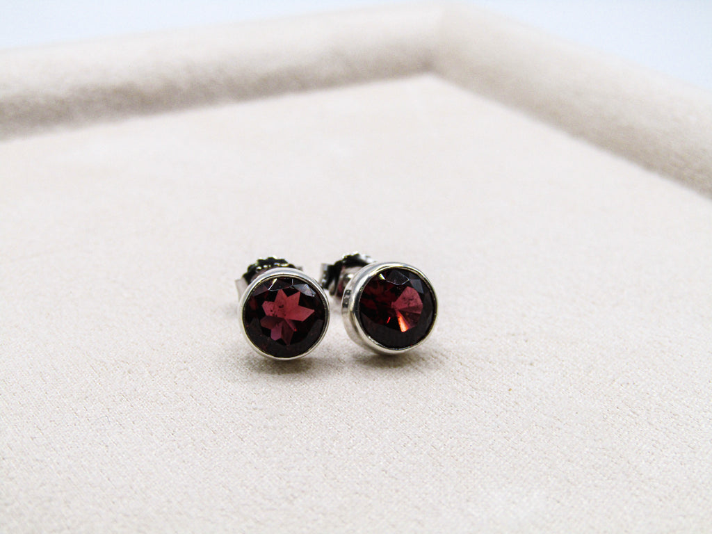 Silver earrings with red gemstones on a white surface