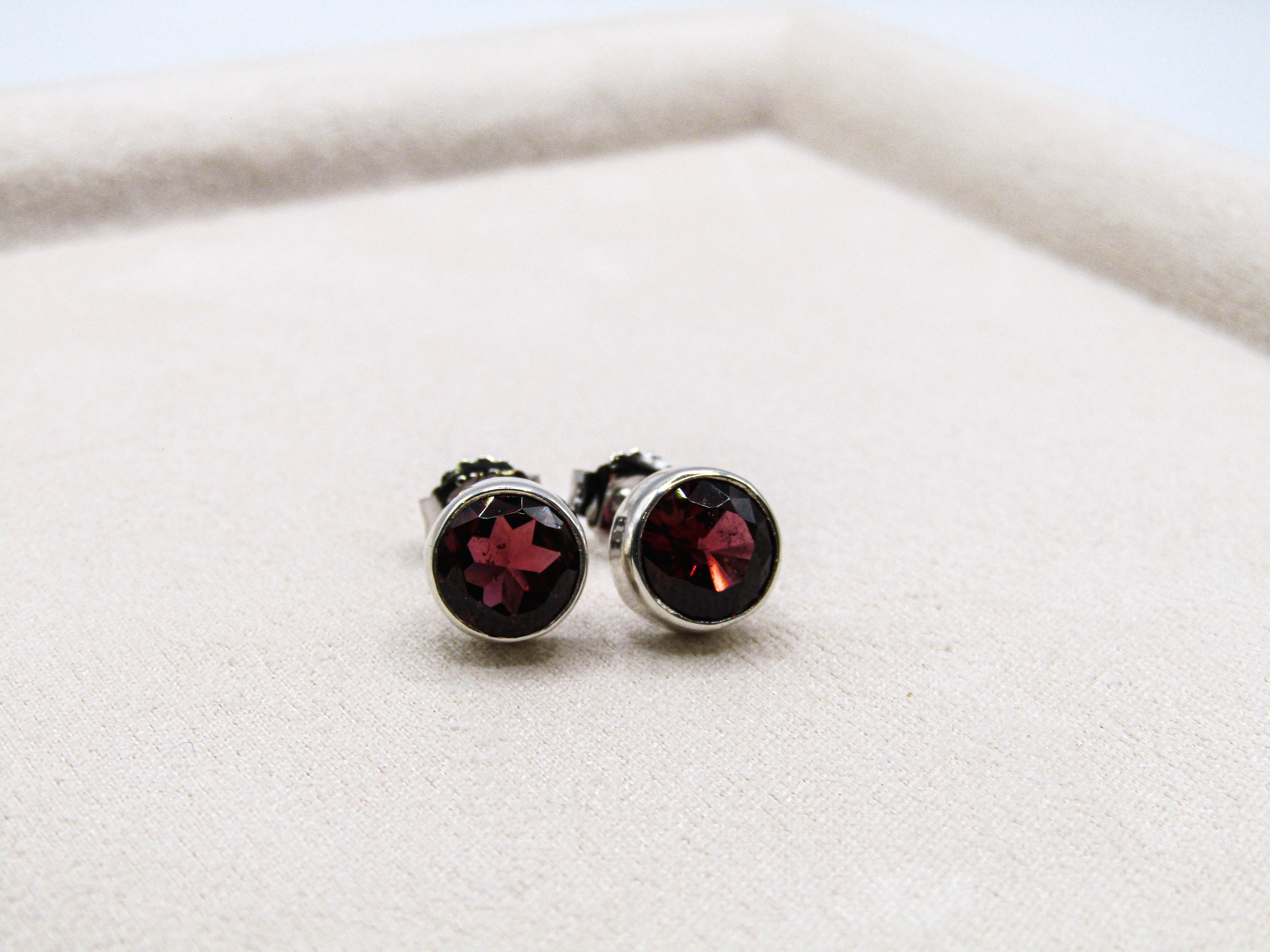 Silver earrings with red gemstones on a white surface