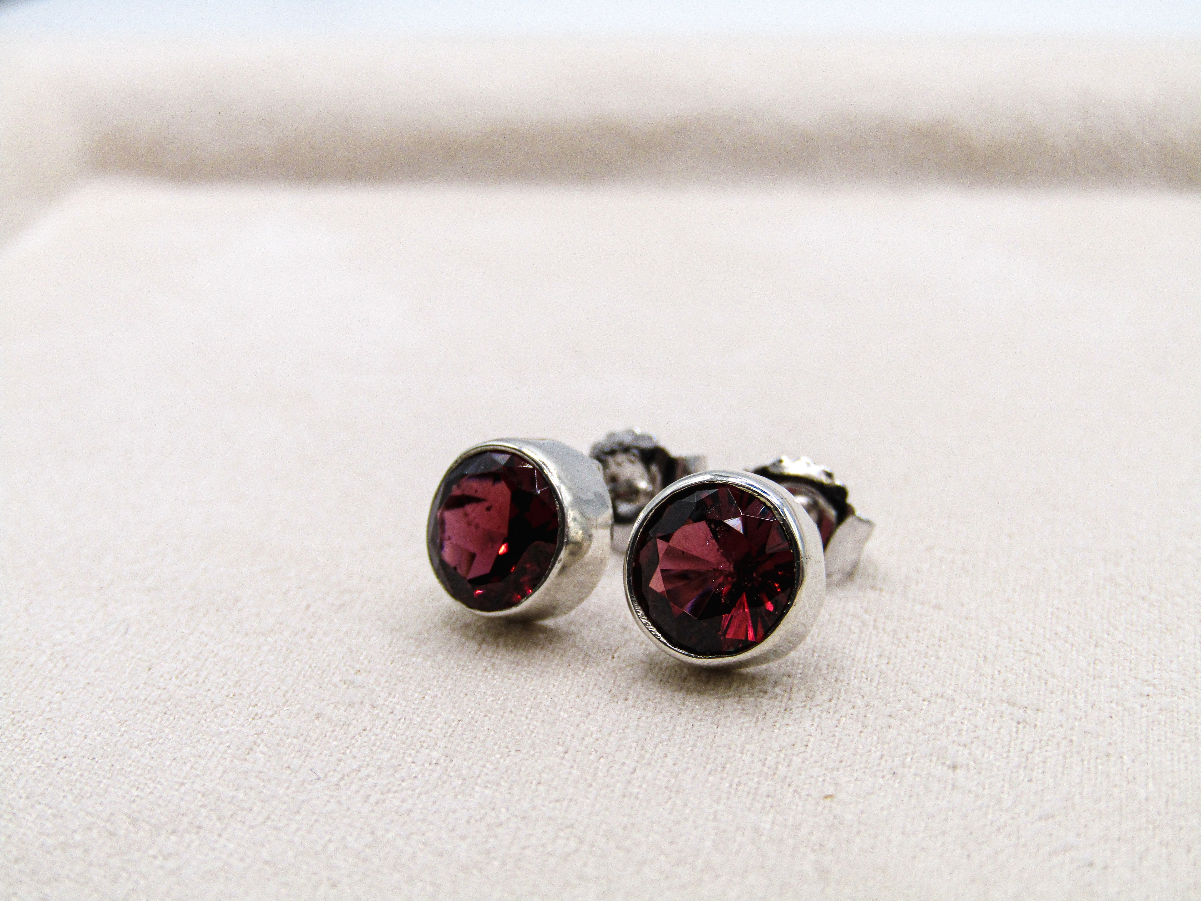 Silver earrings with red gemstones on a white background
