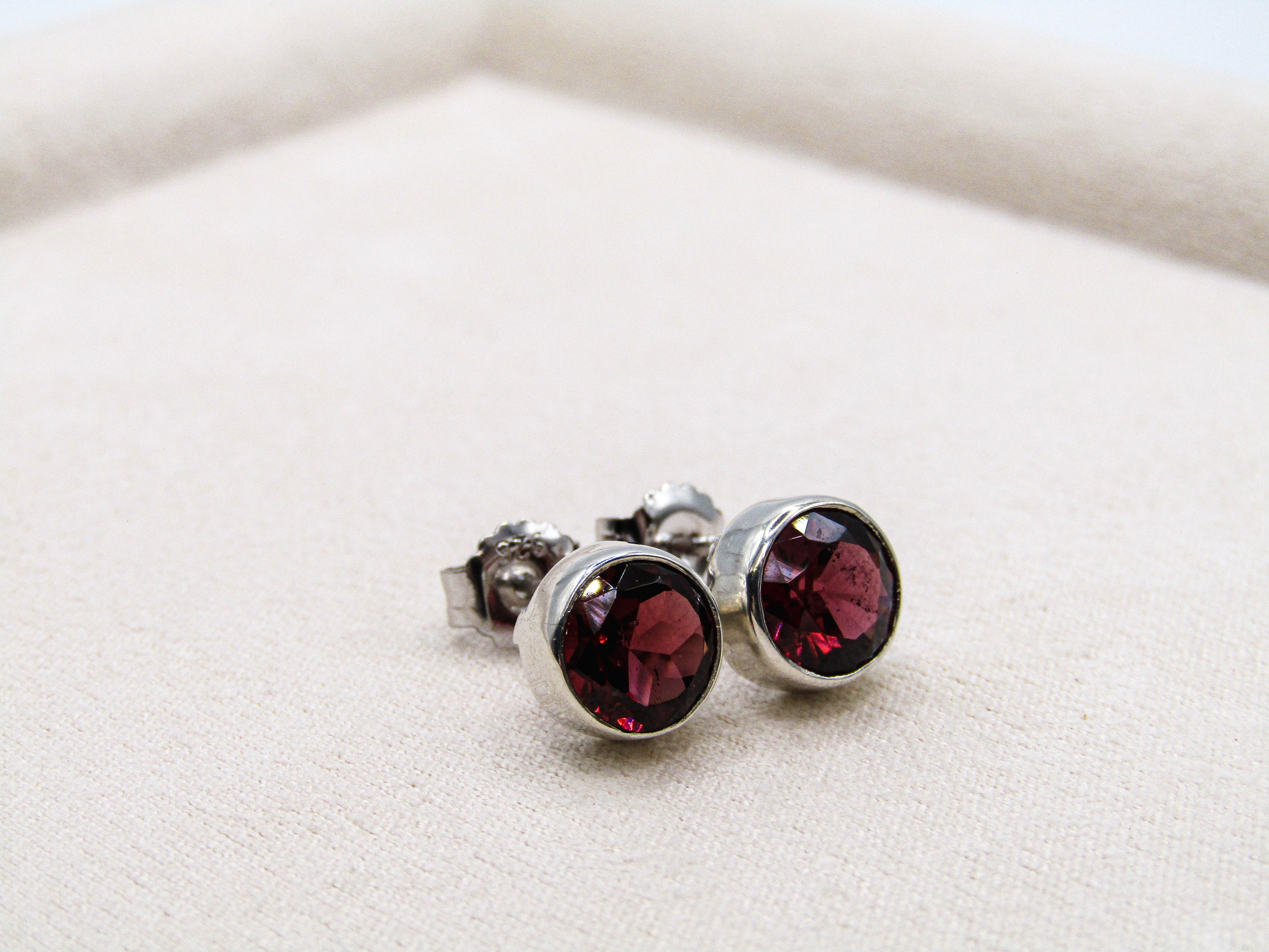 Silver earrings with red gemstones on a white surface