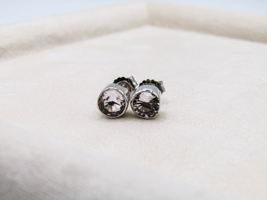 Pair of silver earrings with clear gemstones on a white cushion