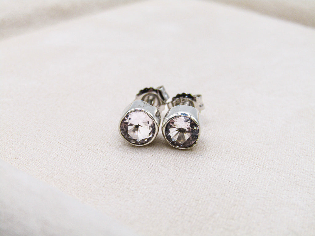 Silver earrings with clear gemstones on a light fabric background