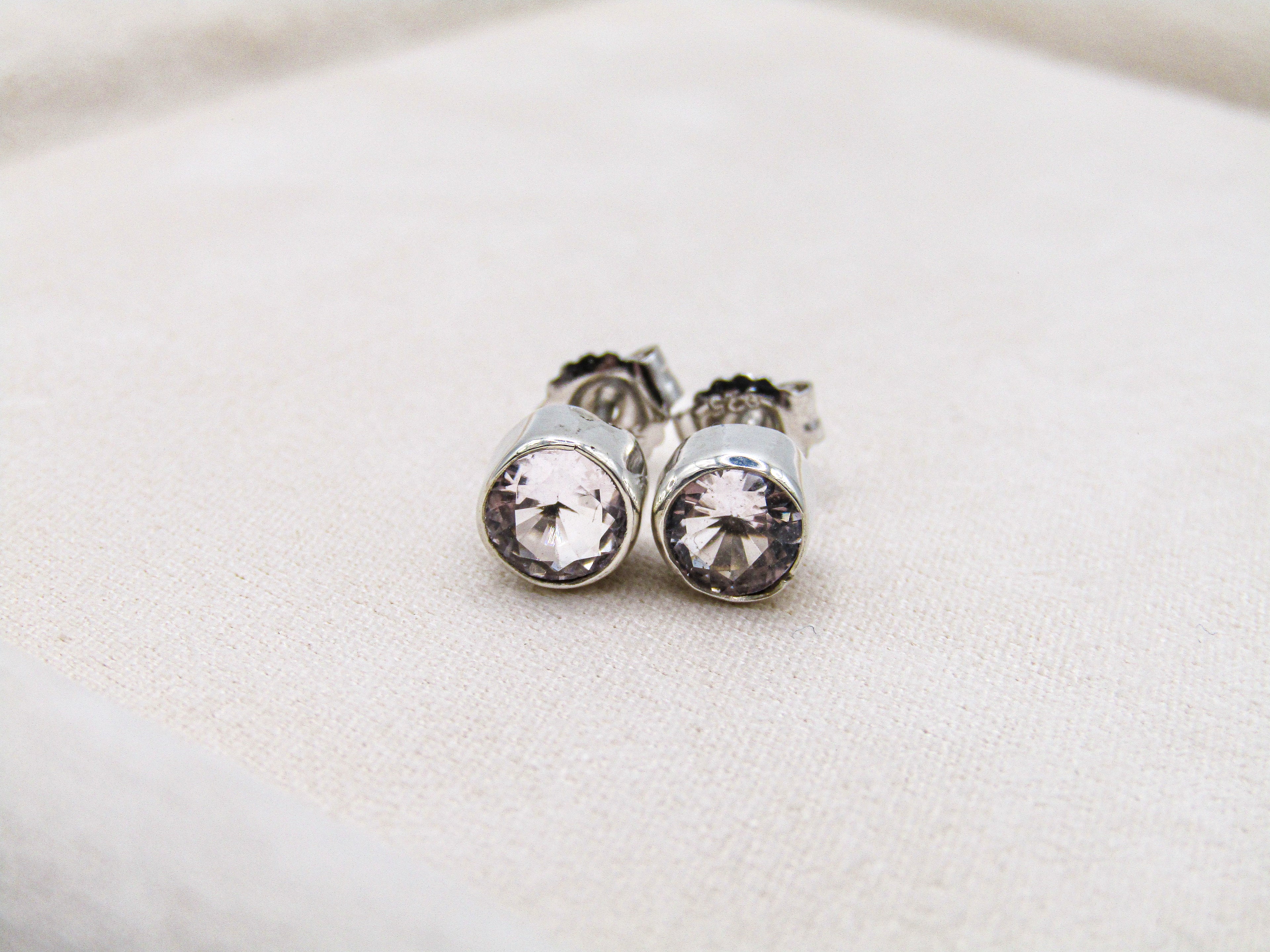 Silver earrings with clear gemstones on a light fabric background