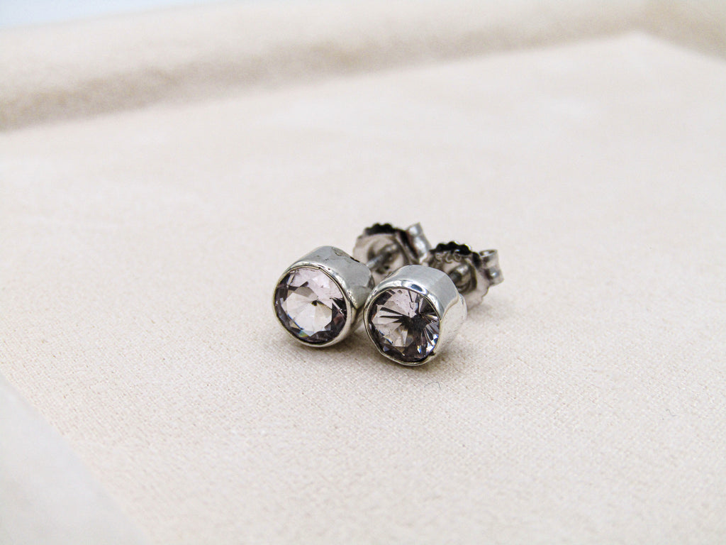 Silver stud earrings with clear gemstones on a light beige background