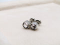 Silver stud earrings with clear gemstones on a light beige background