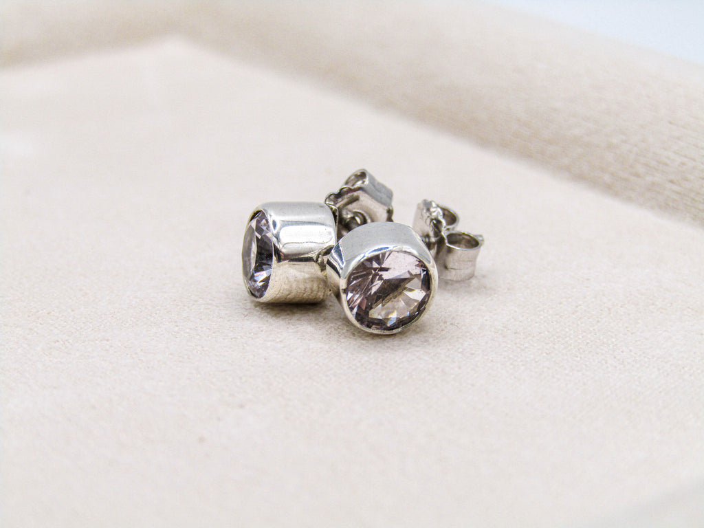 Silver earrings with clear gemstones on a light beige fabric background
