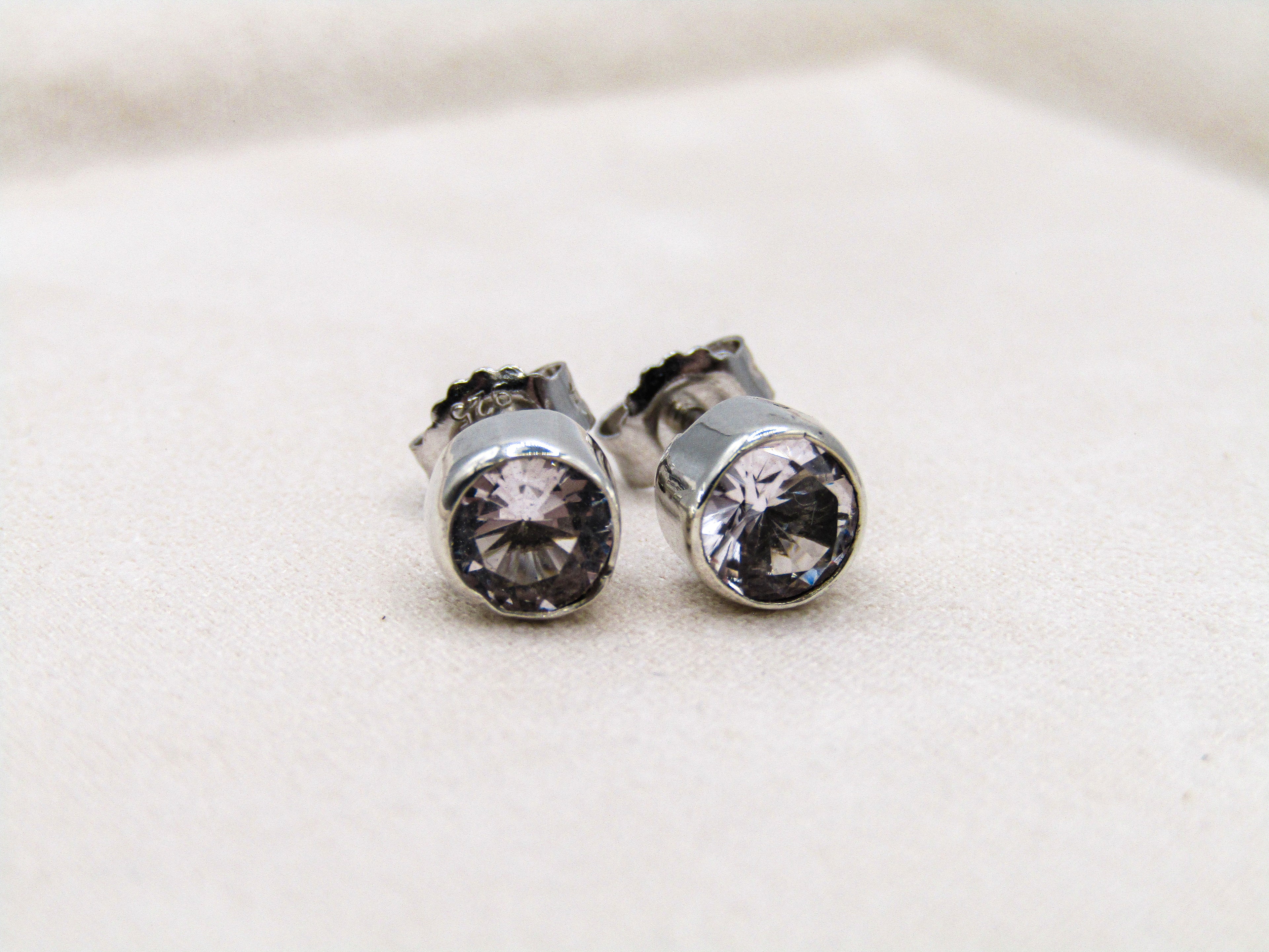 Pair of silver earrings with clear gemstones on a light background