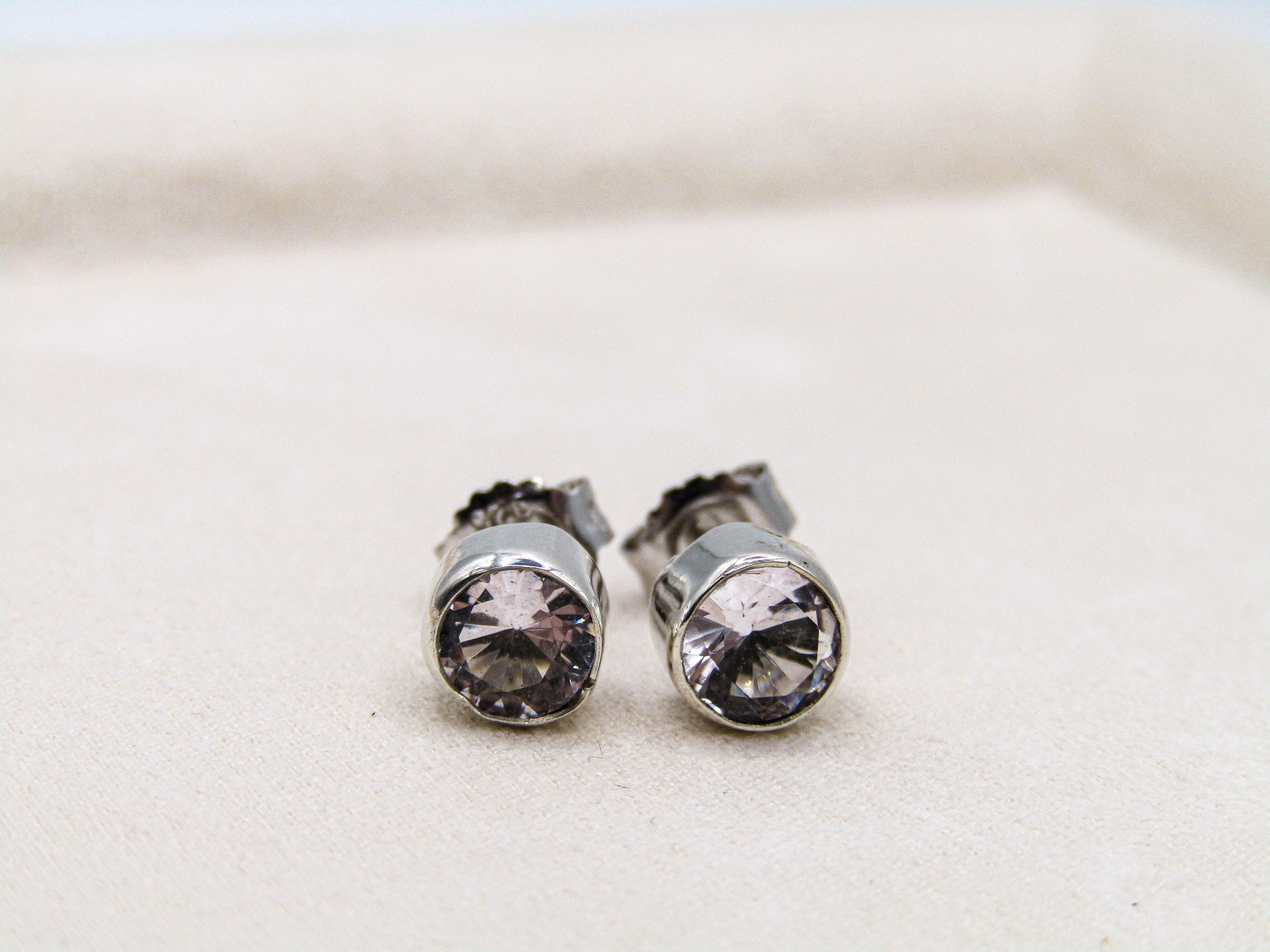 Pair of silver stud earrings with clear gemstones on a light background