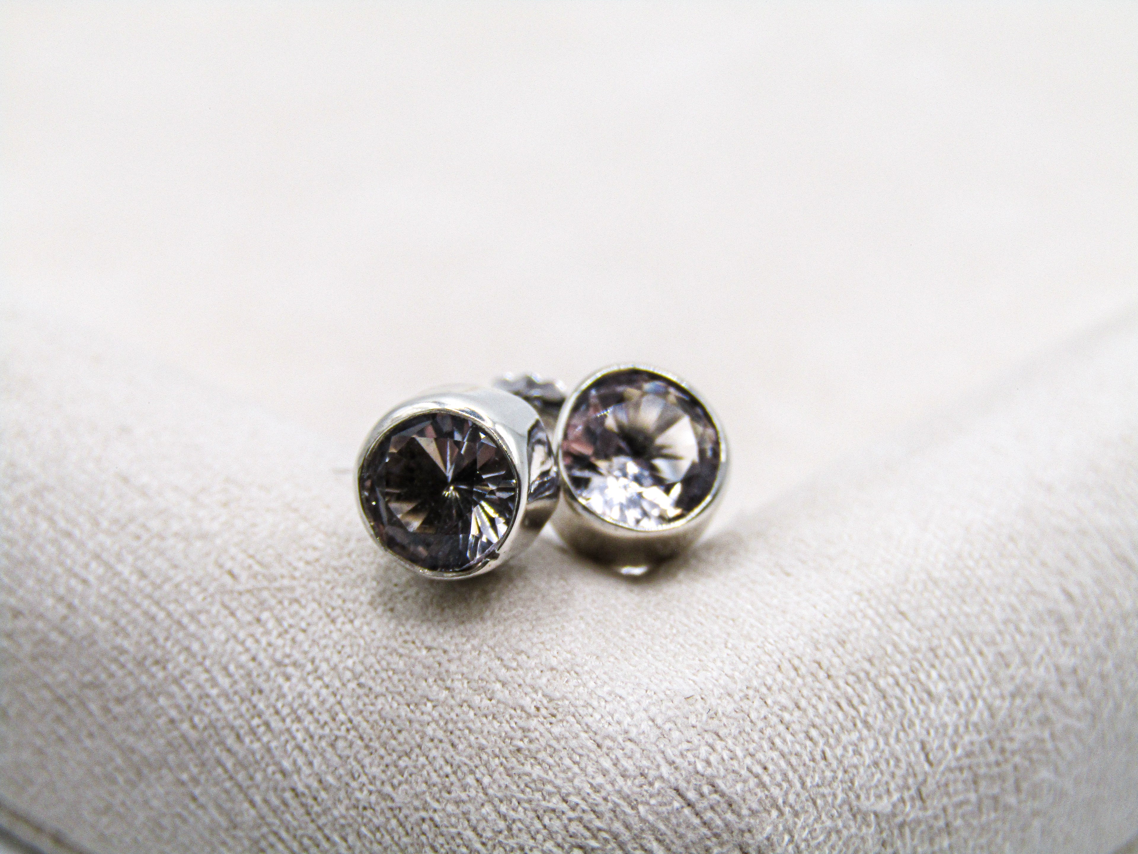Silver stud earrings with clear gemstones on a light gray background
