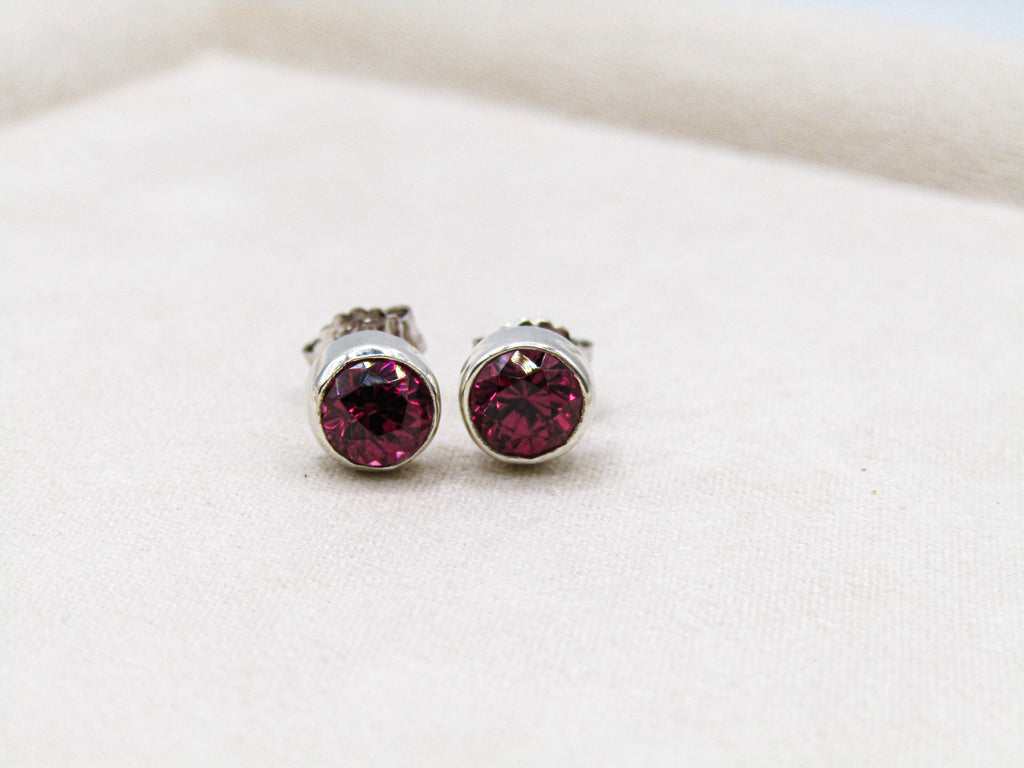 Silver stud earrings with red gemstones on a white background