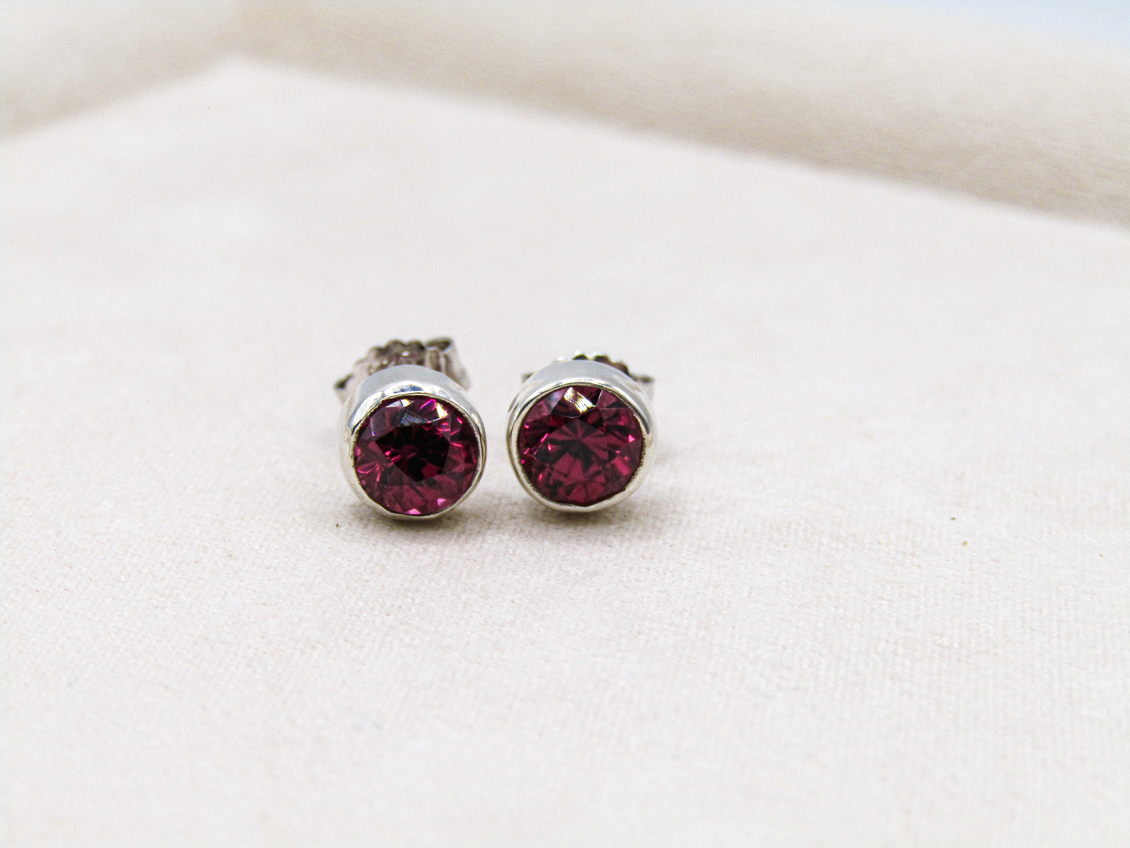 Silver stud earrings with red gemstones on a white background