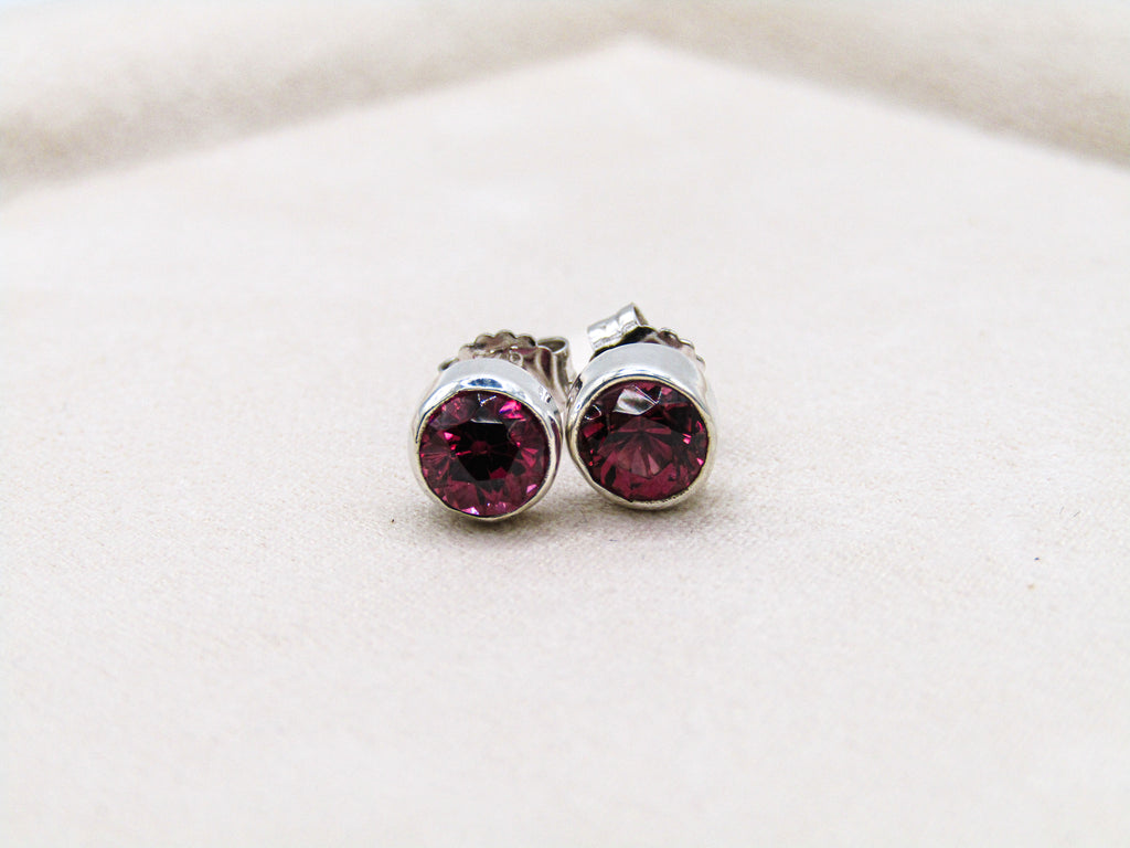 Silver earrings with red gemstones on a white background