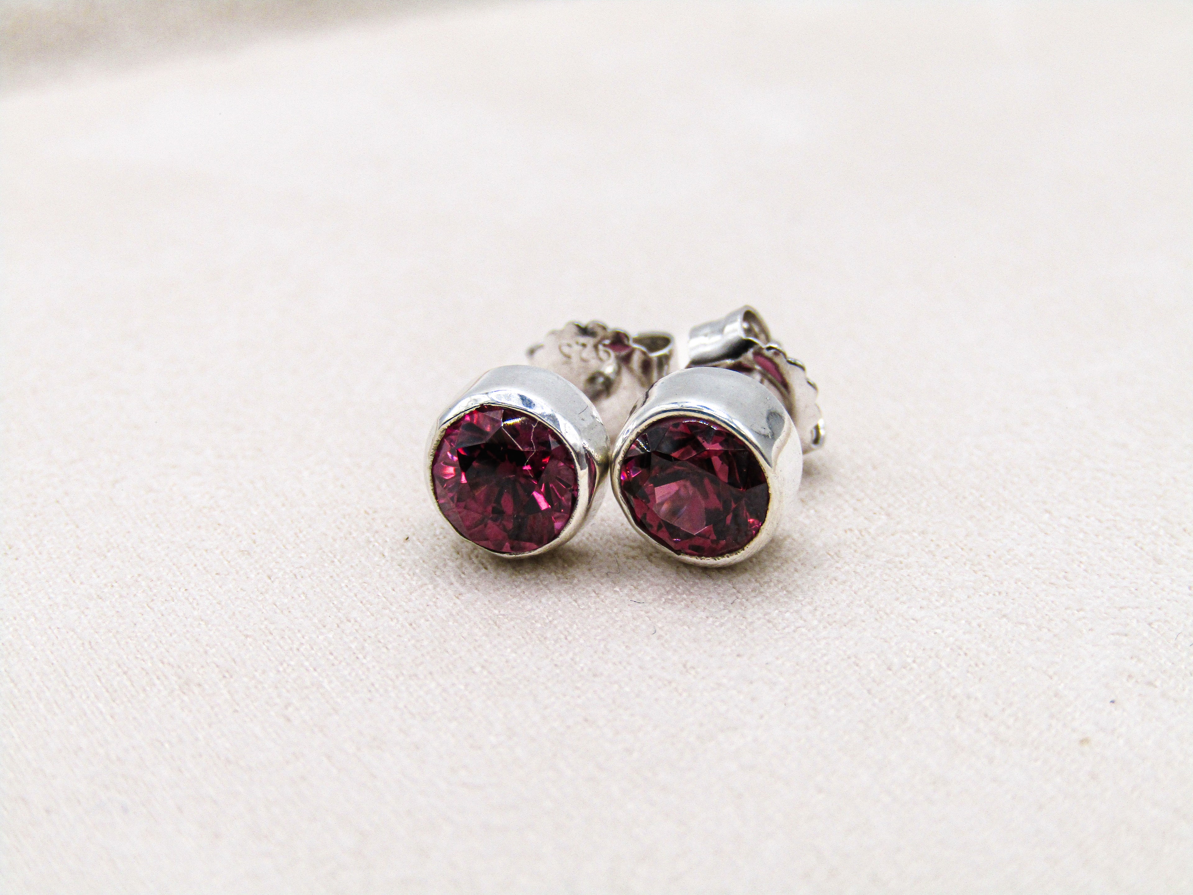 Silver earrings with red gemstones on a light beige background