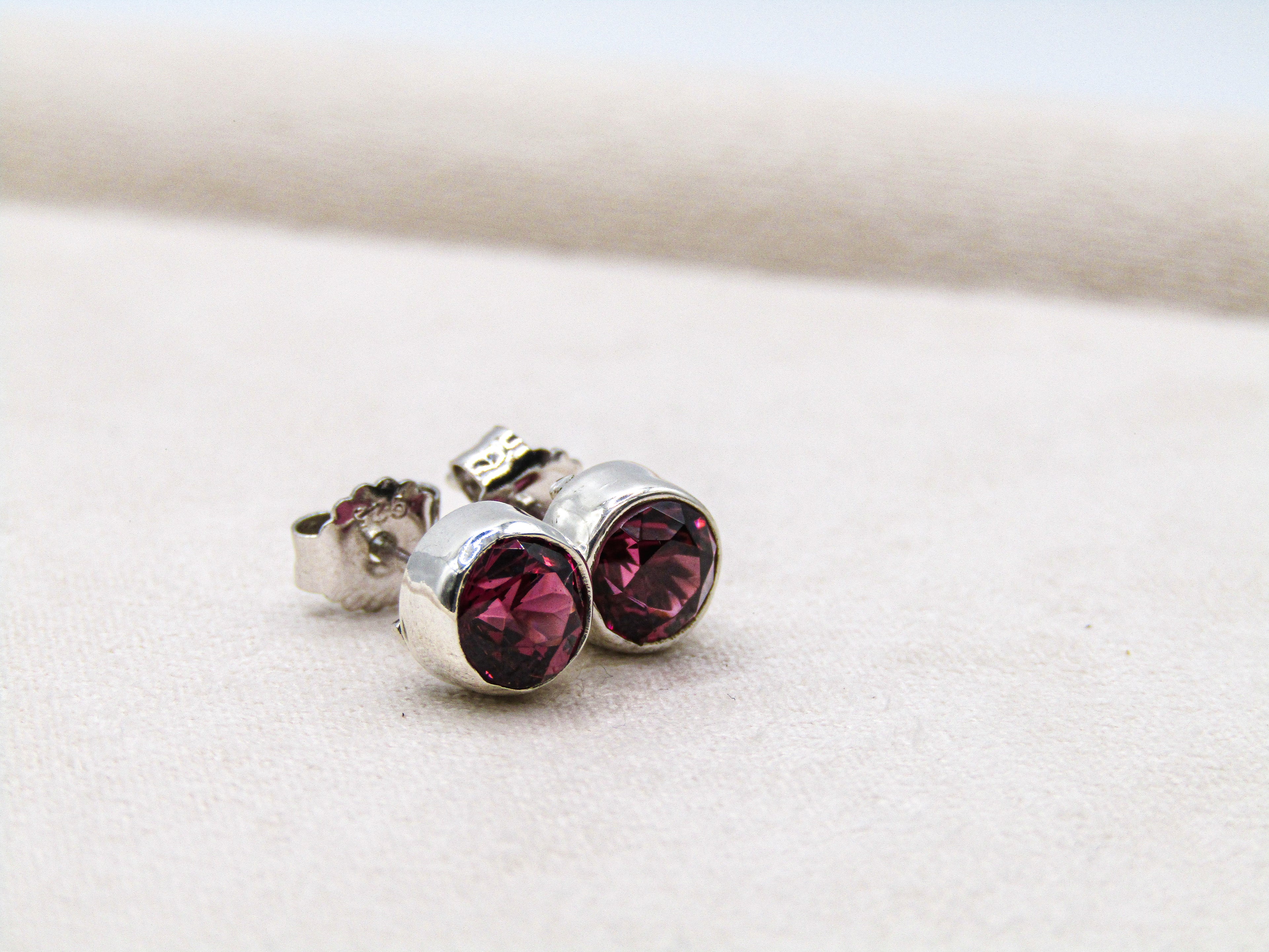 Silver earrings with red gemstones on a light background