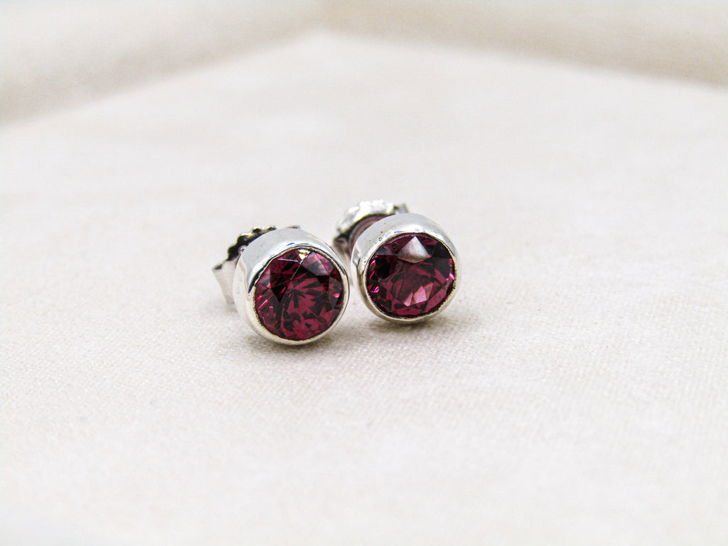 Silver stud earrings with red gemstones on a white background