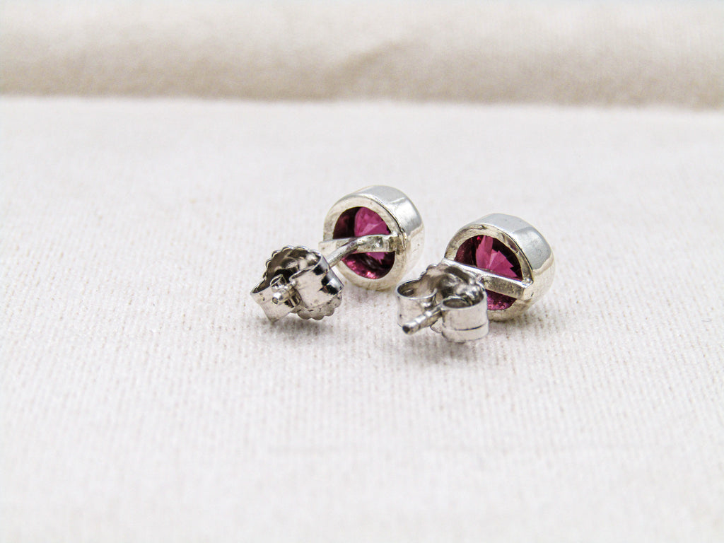 Silver earrings with pink gemstones on a white fabric background