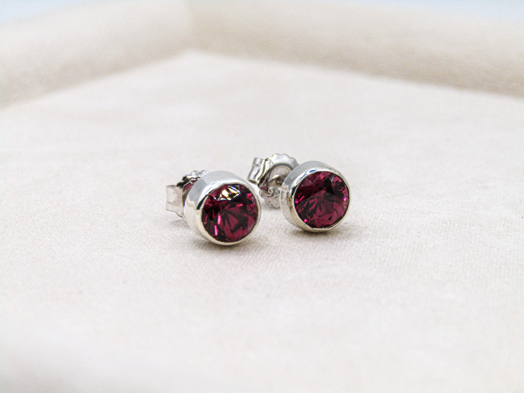 Silver earrings with red gemstones on a white background