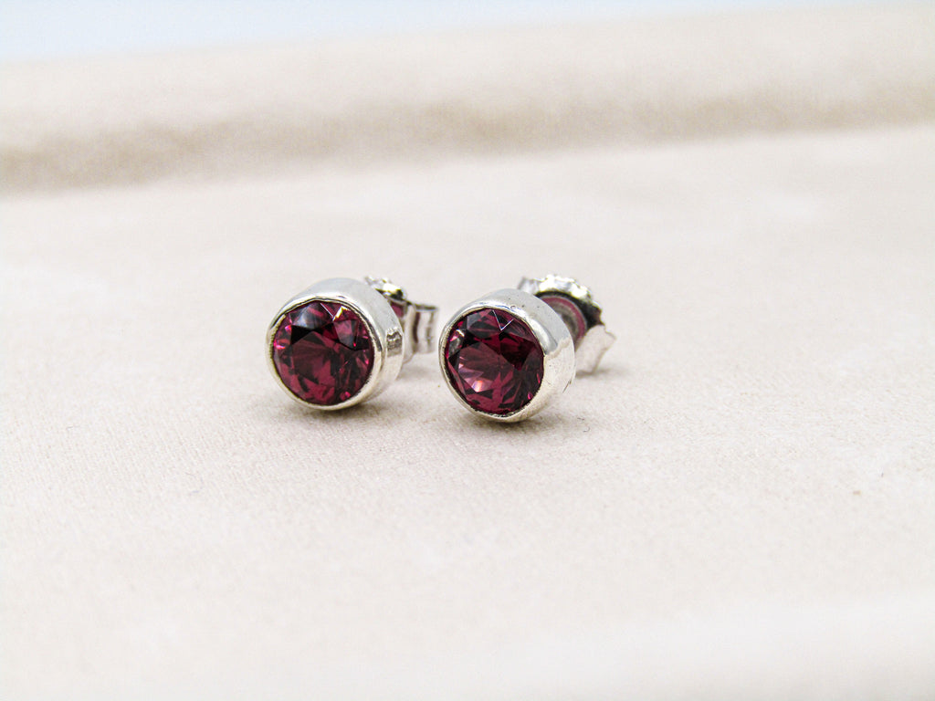 Silver stud earrings with red gemstones on a light background