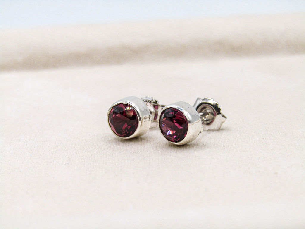 Silver earrings with red gemstones on a light background