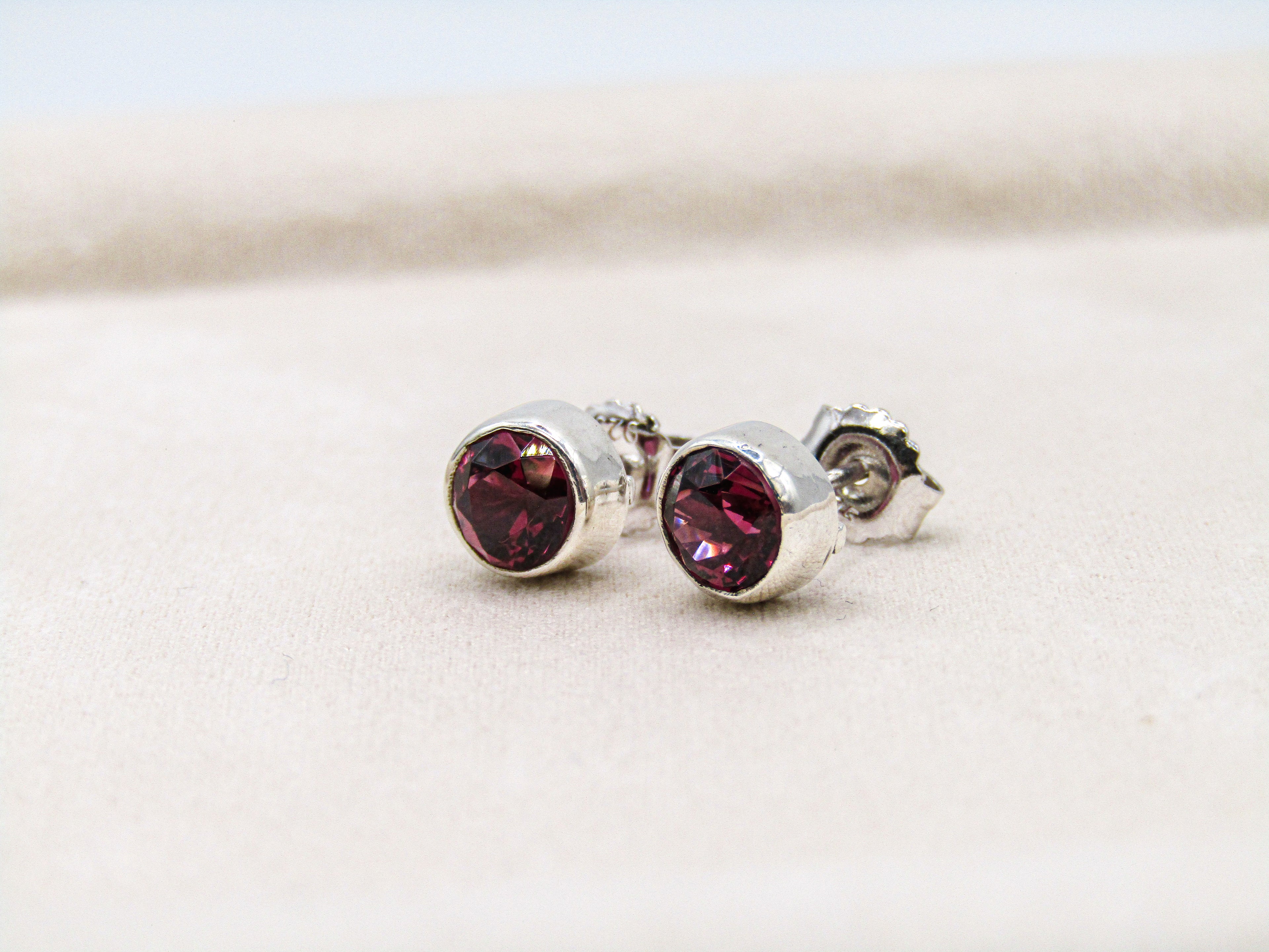 Silver earrings with red gemstones on a light background