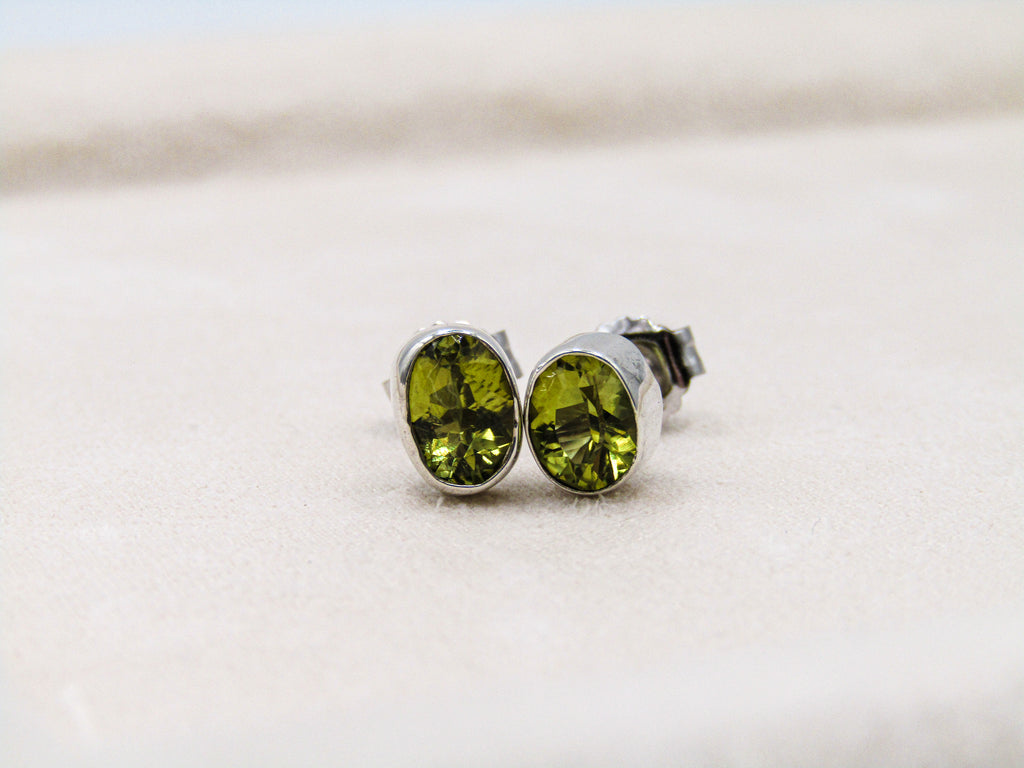 Green gemstone stud earrings on a light background