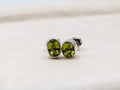 Green gemstone stud earrings on a light background