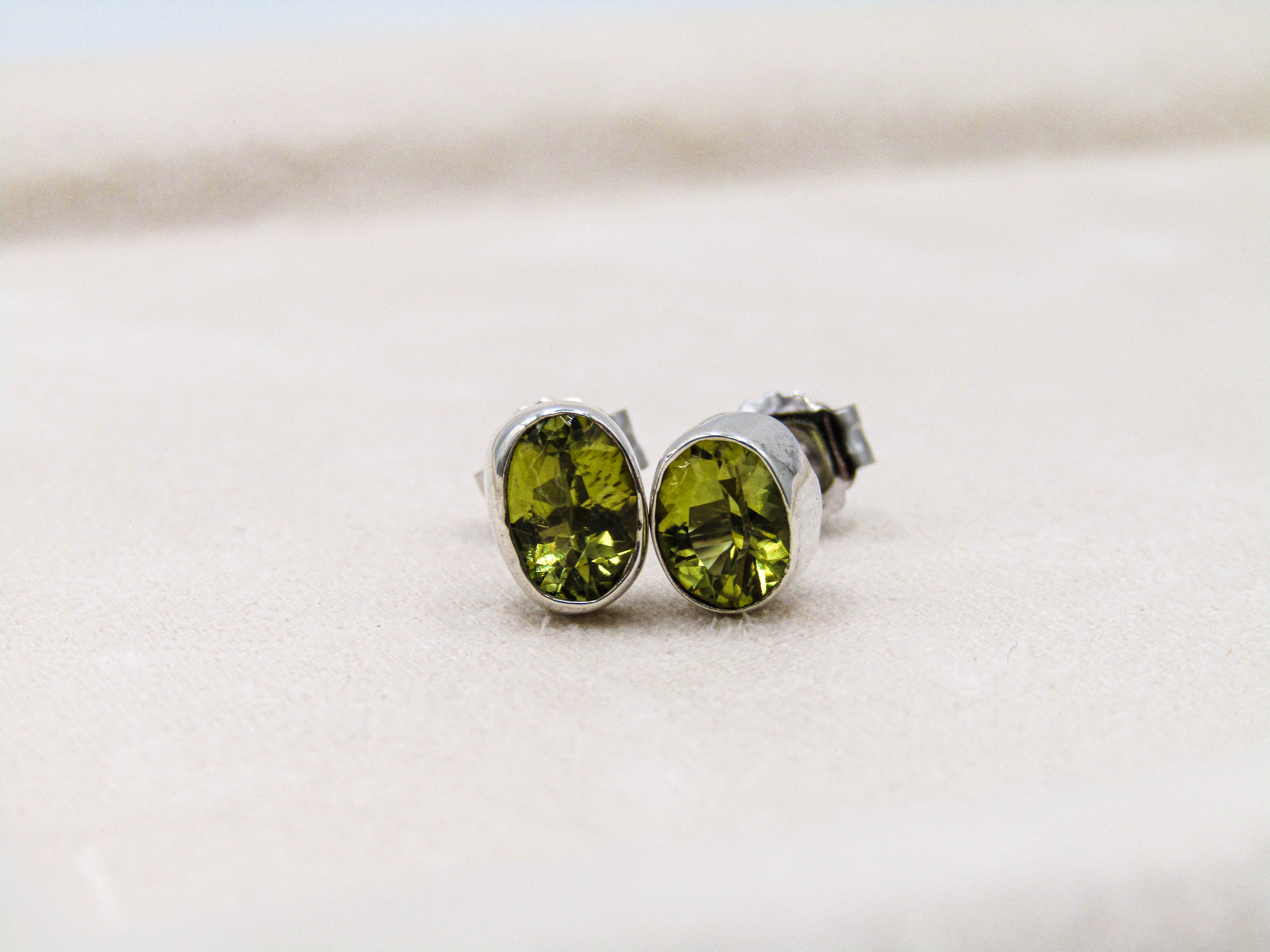 Green gemstone stud earrings on a light background