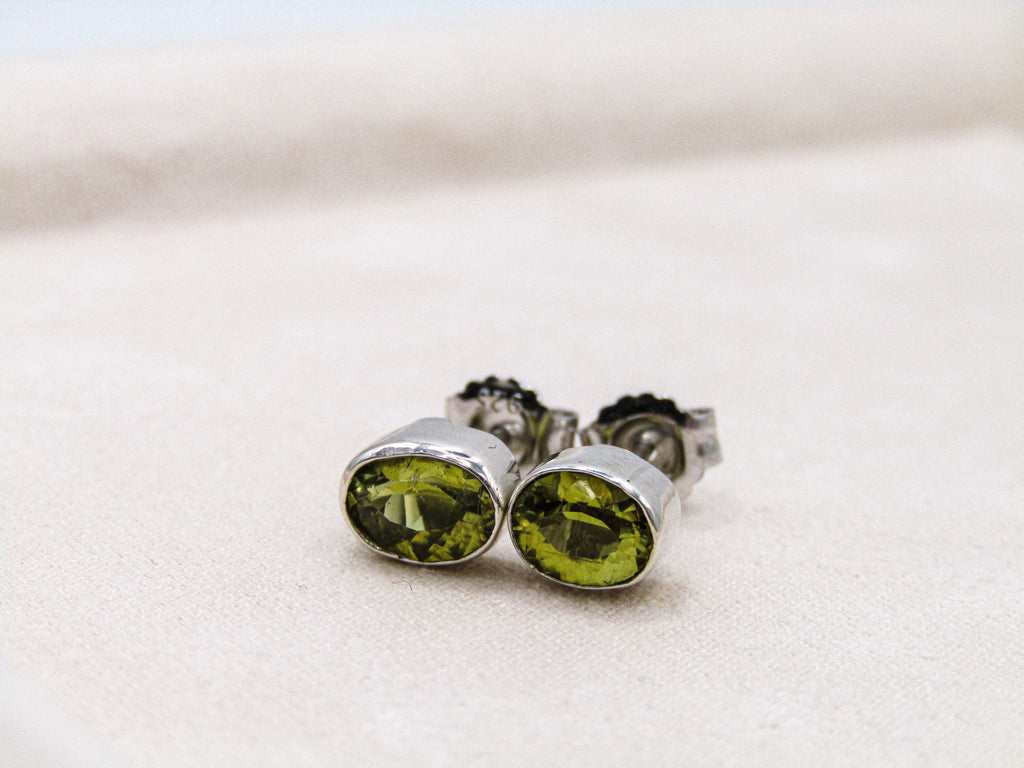Silver earrings with green gemstones on a light background