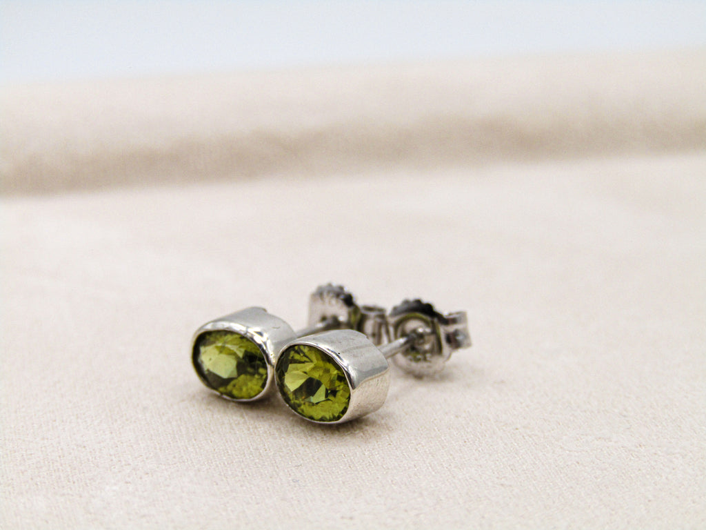 Silver earrings with green gemstones on a light background