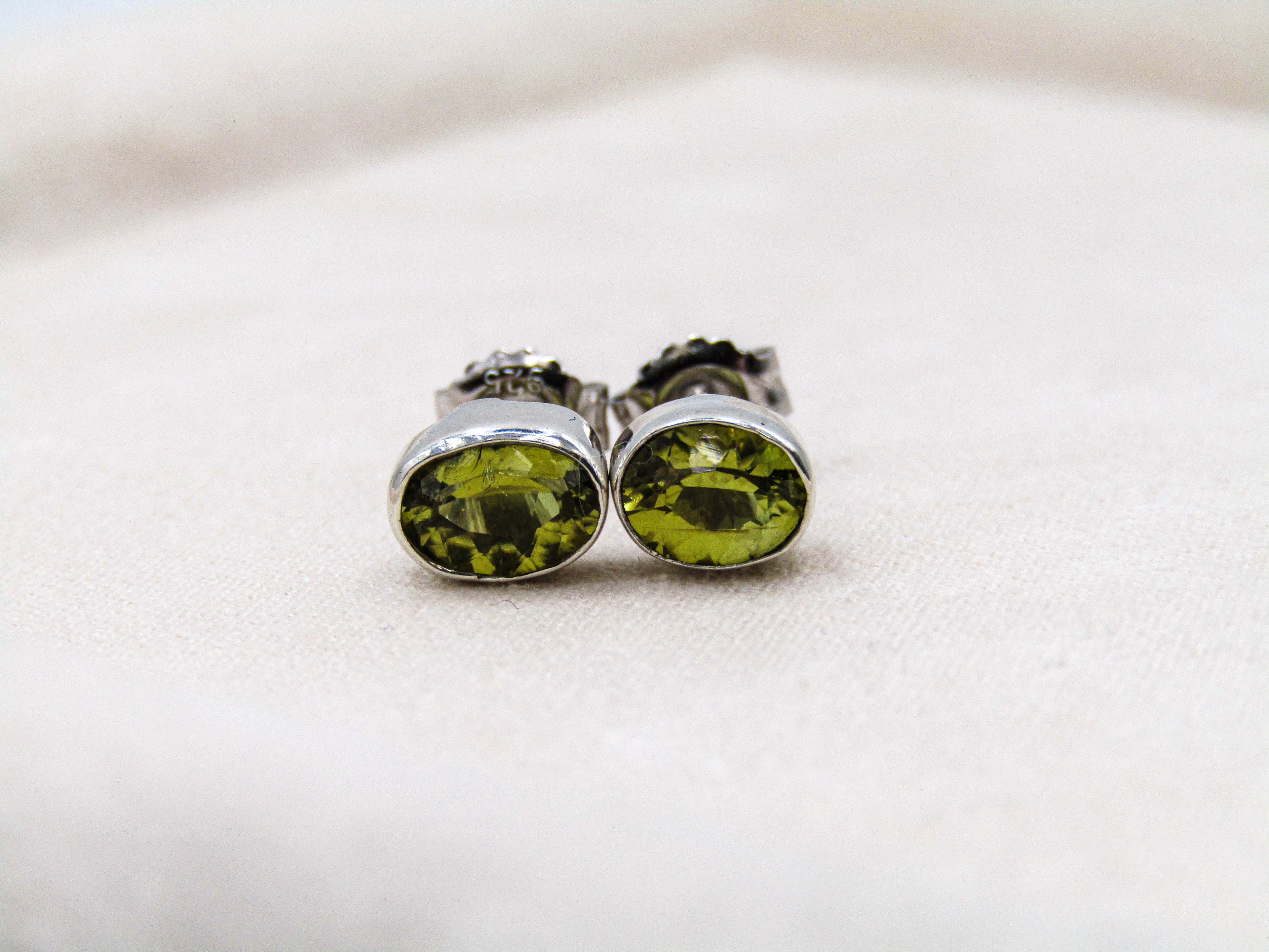 Pair of green gemstone stud earrings on a light background