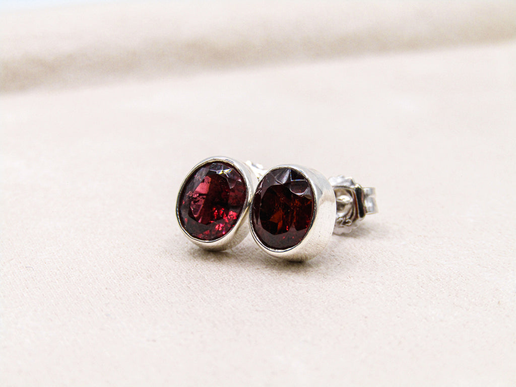 Silver earrings with red gemstones on a light beige background