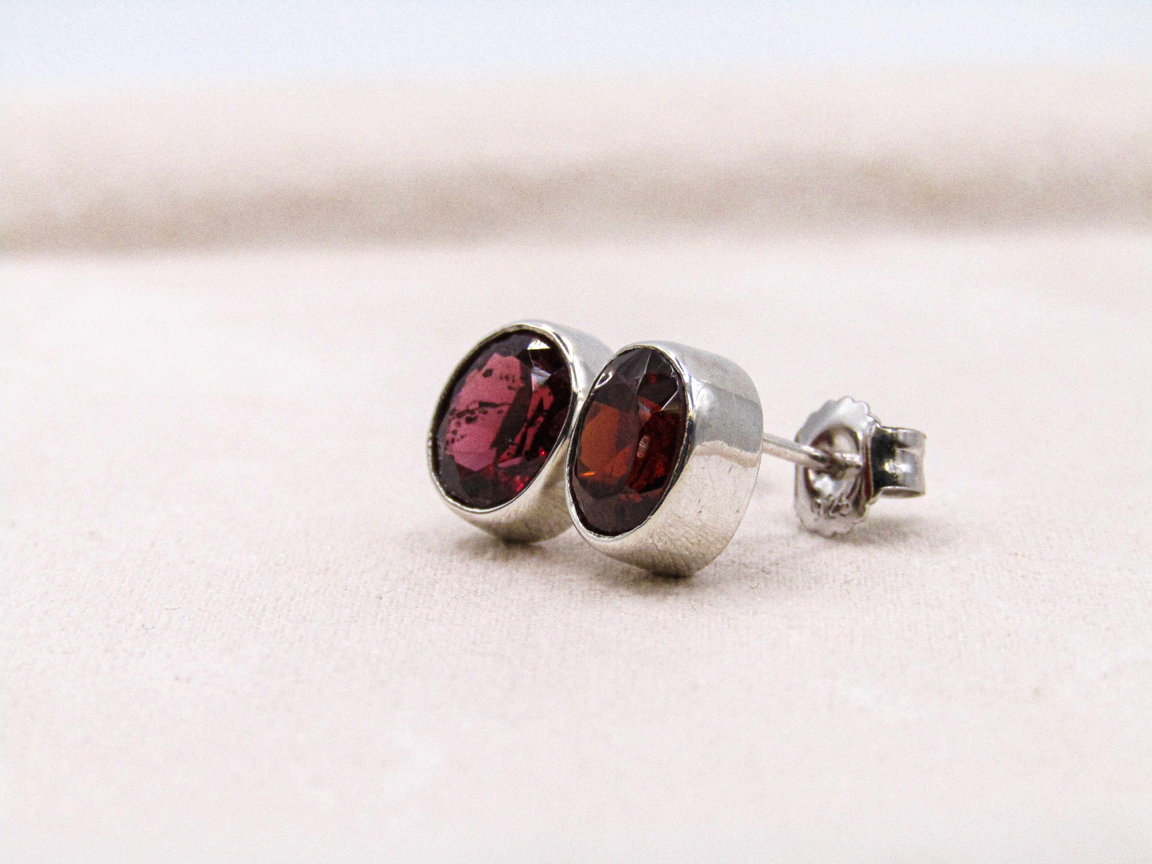 Silver earrings with red gemstones on a light background