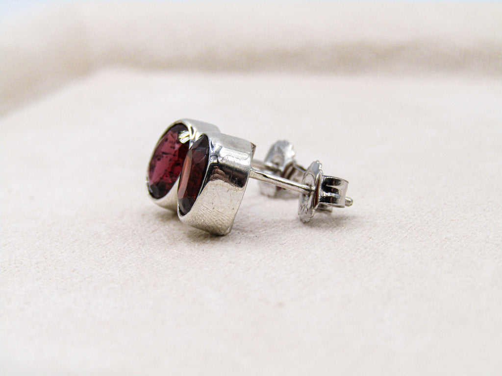 Silver earring with a red gemstone on a light background