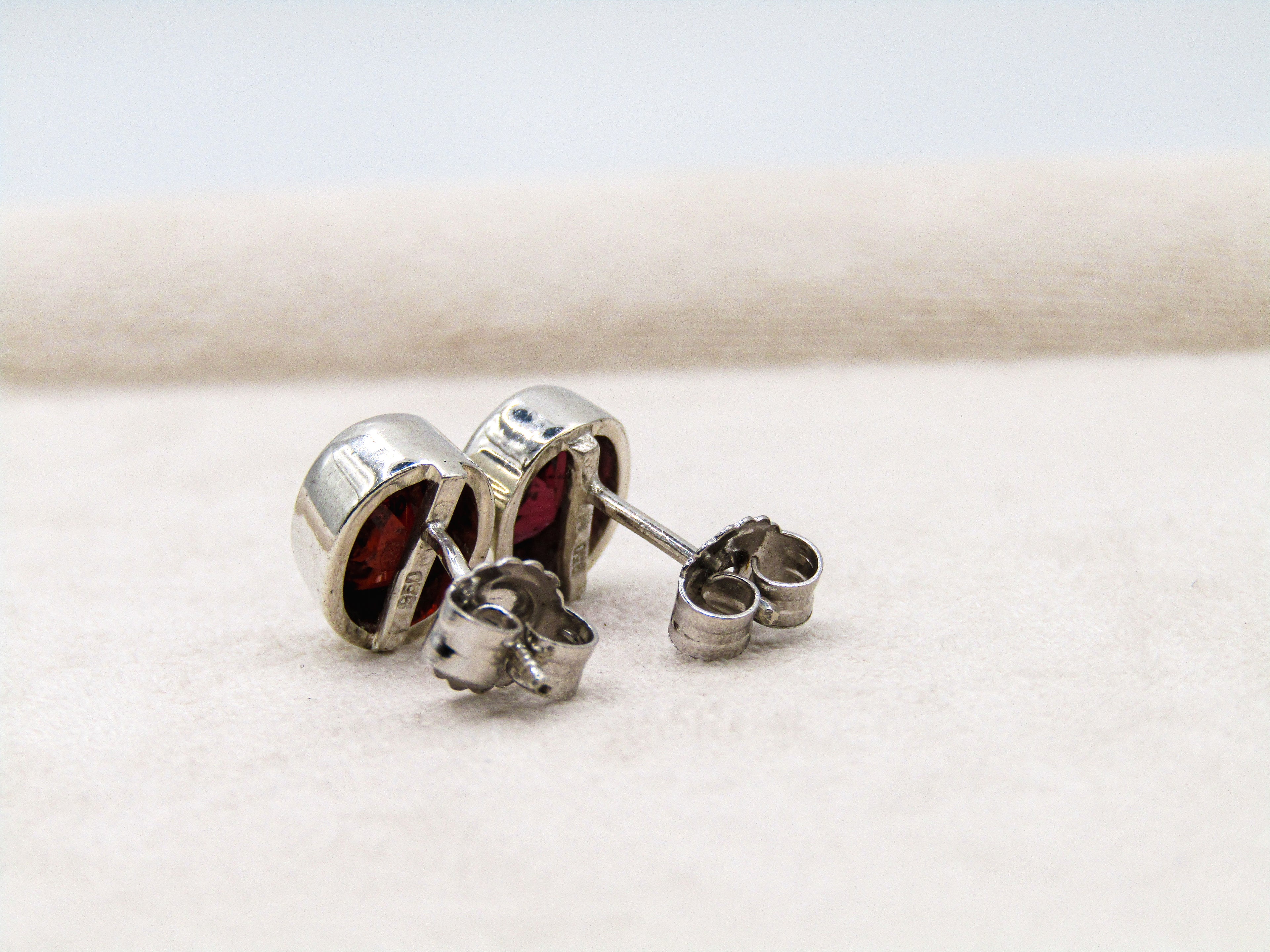 Silver earrings with red gemstones on a white background