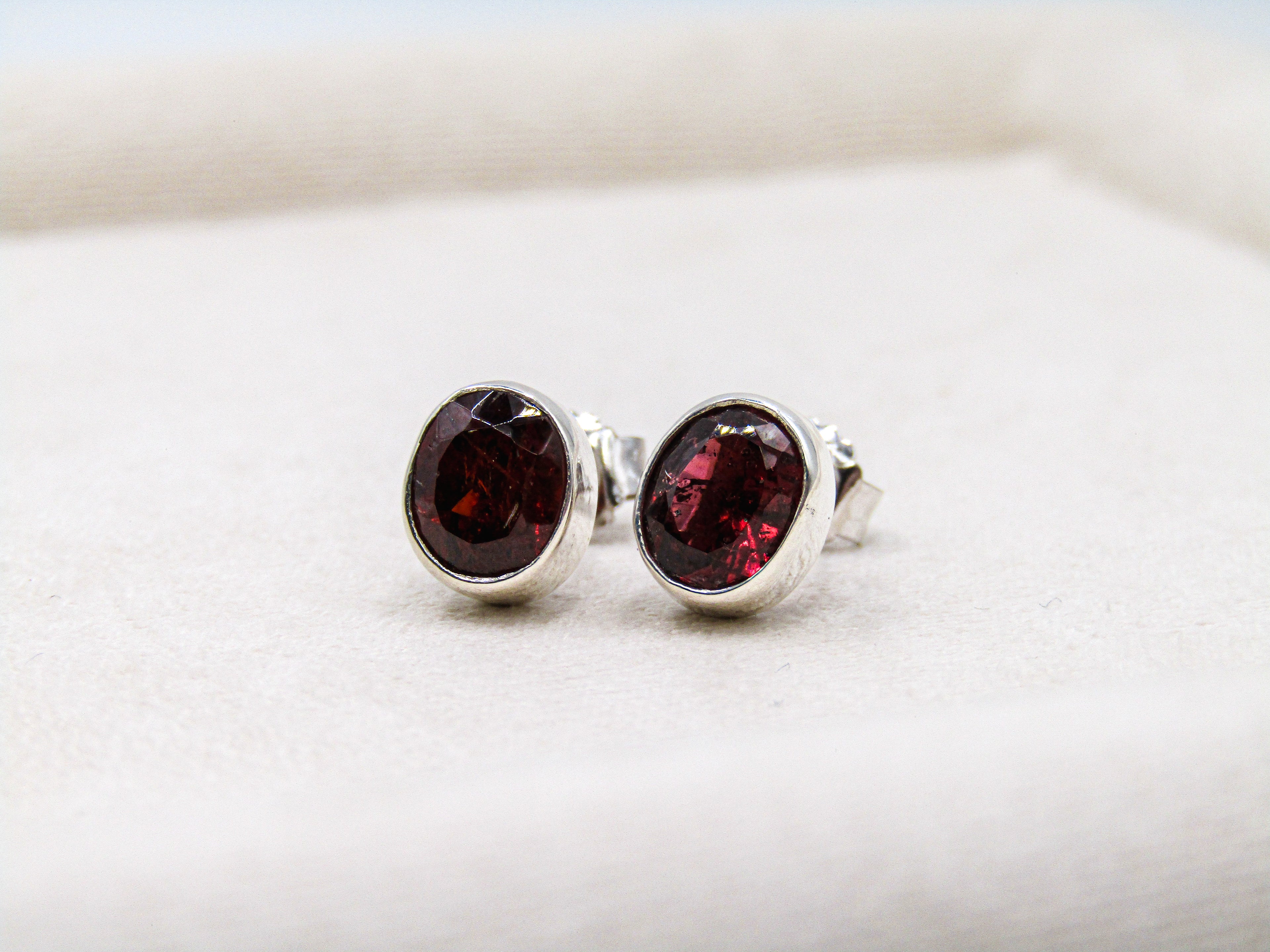 Silver earrings with red gemstones on a white background