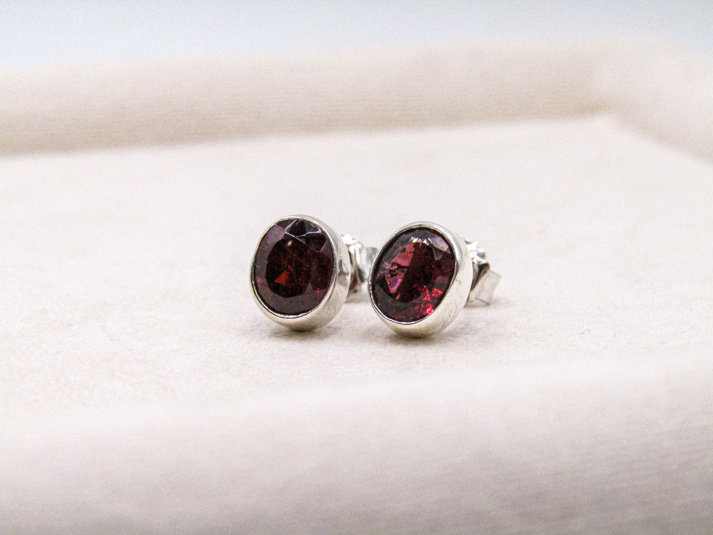 Silver earrings with red gemstones on a white background