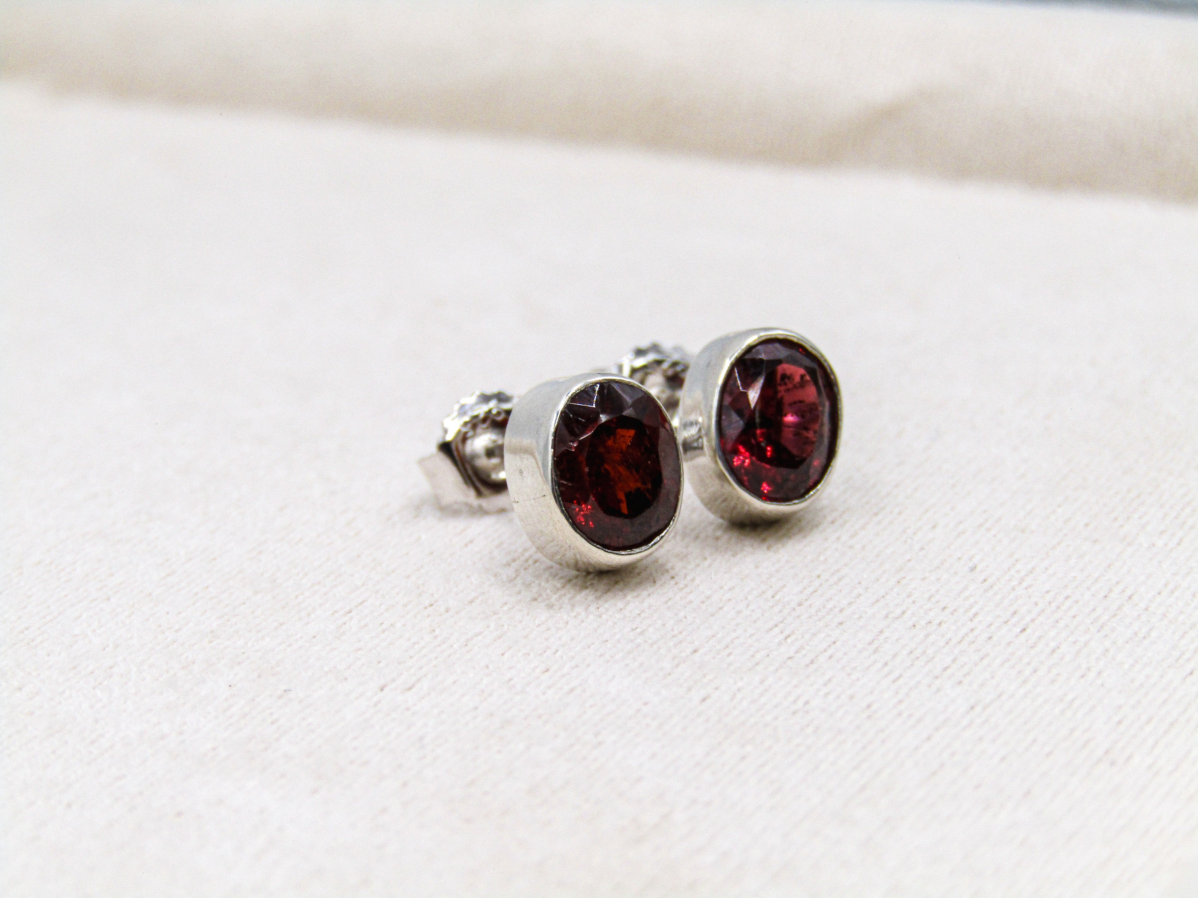 Pair of silver earrings with red gemstones on a white surface