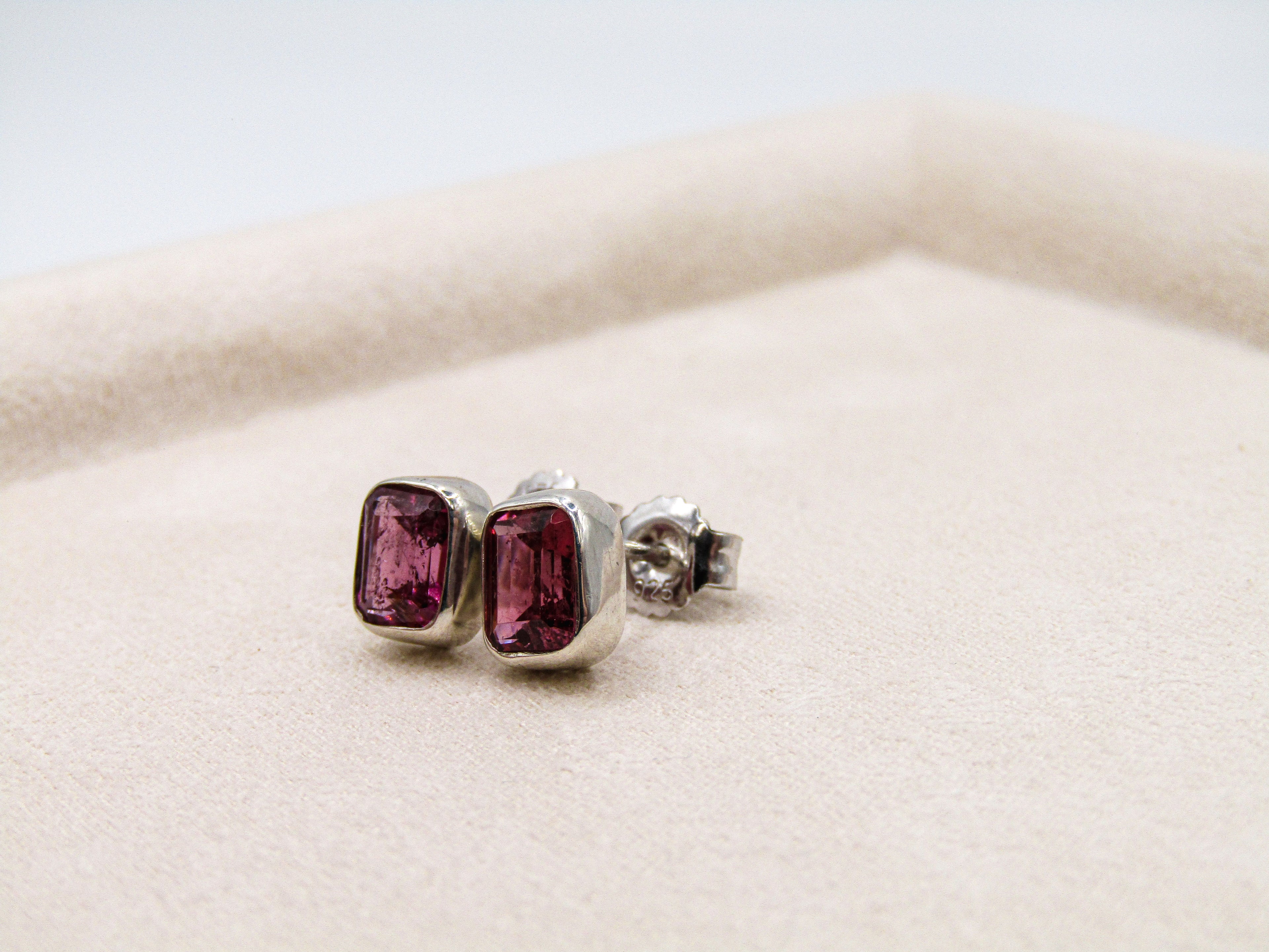 Pair of stud earrings with purple gemstones on a white background