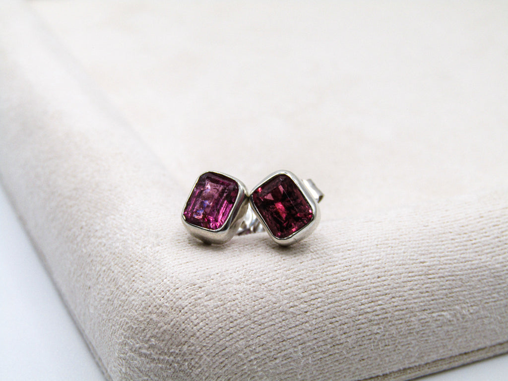 Pair of earrings with pink gemstones on a white cushion