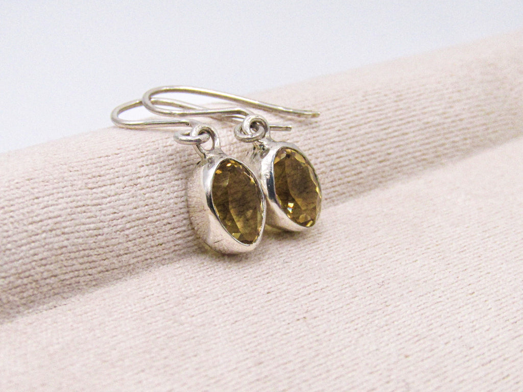 Silver earrings with gemstones on a beige fabric background