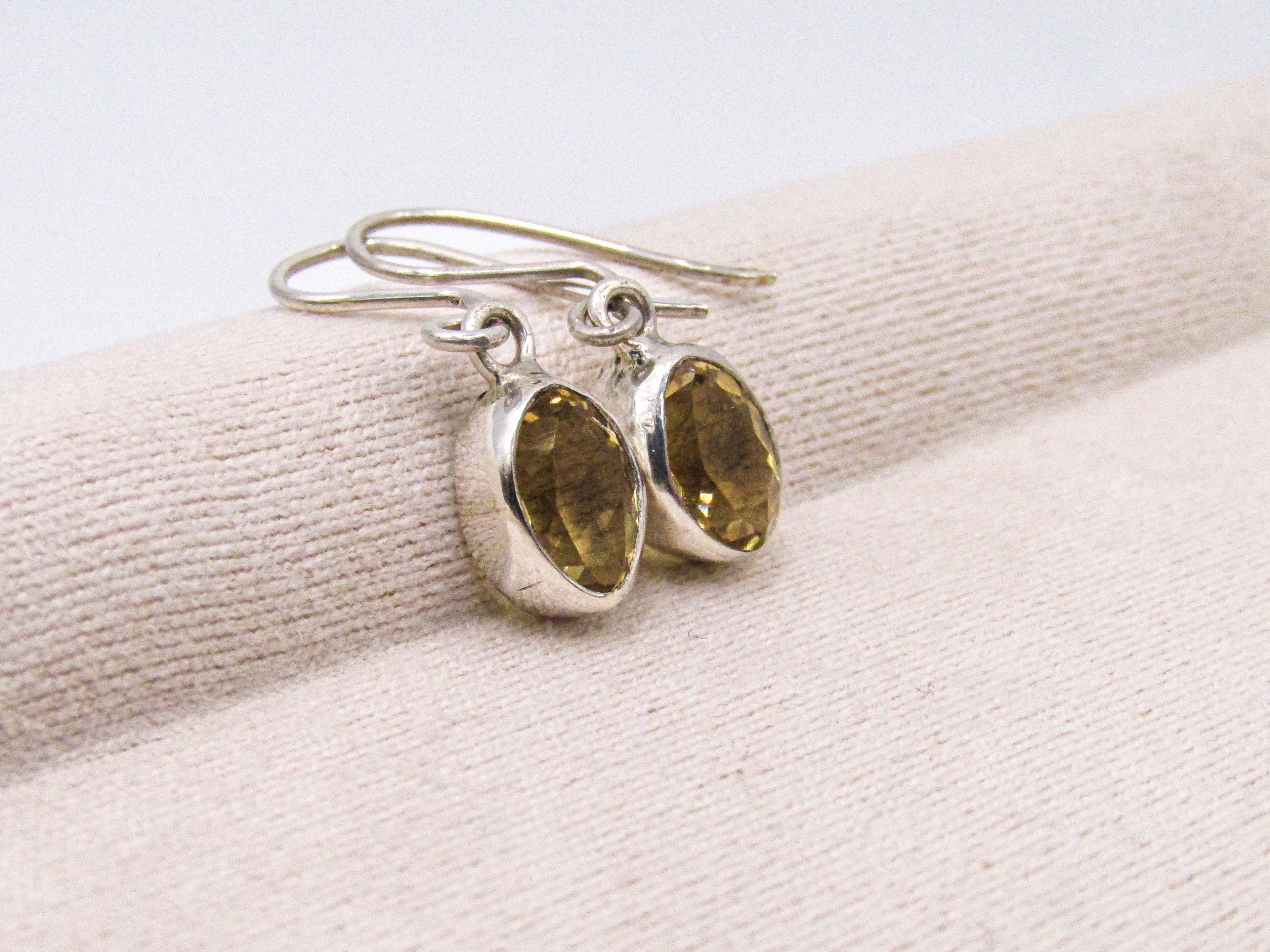 Silver earrings with gemstones on a beige fabric background