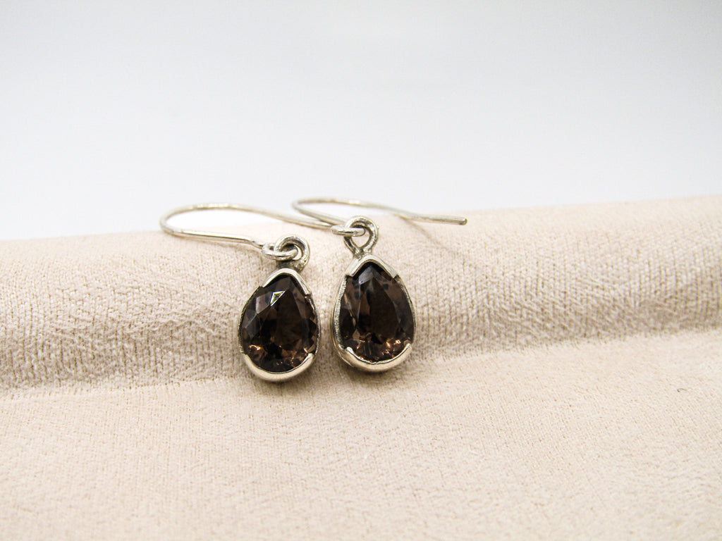 Pair of smoky quartz earrings on a beige fabric background