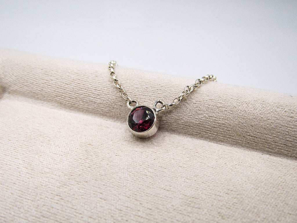 Necklace with a red gemstone pendant on a white surface
