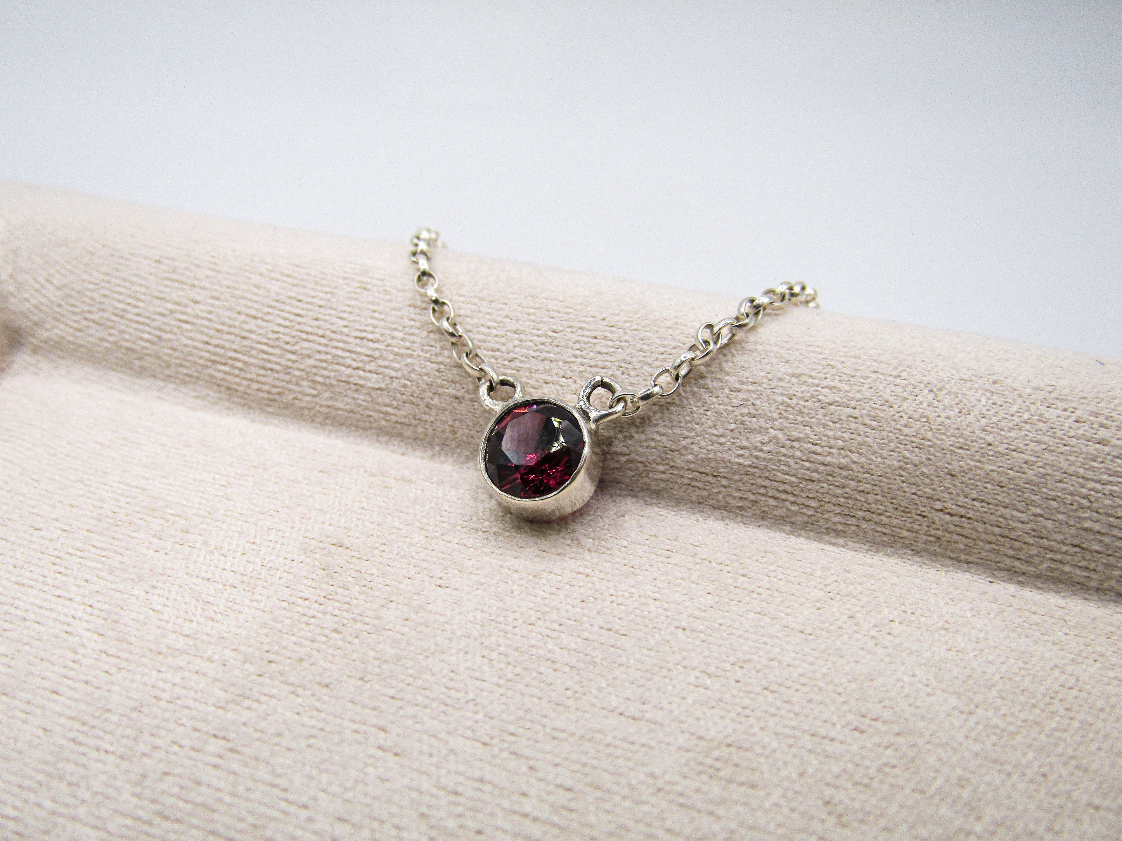 Necklace with a red gemstone pendant on a white surface