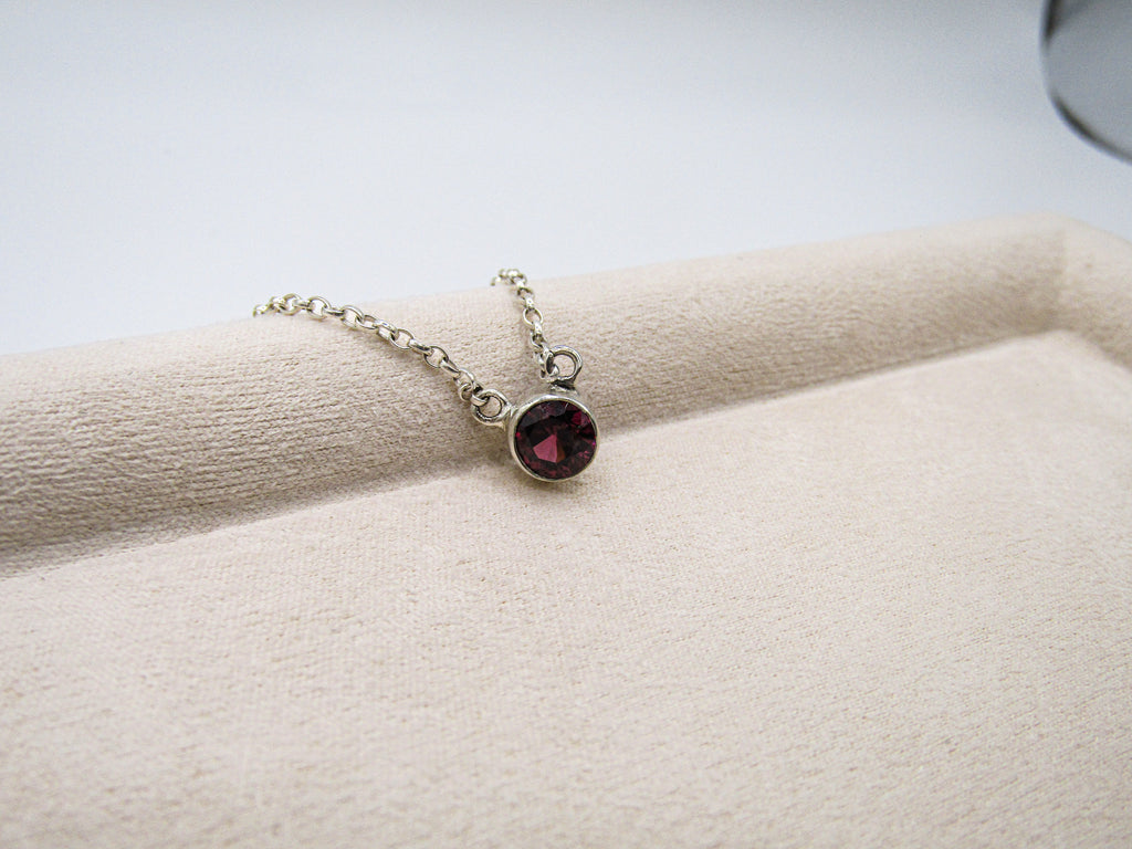 Necklace with a red gemstone pendant on a white surface