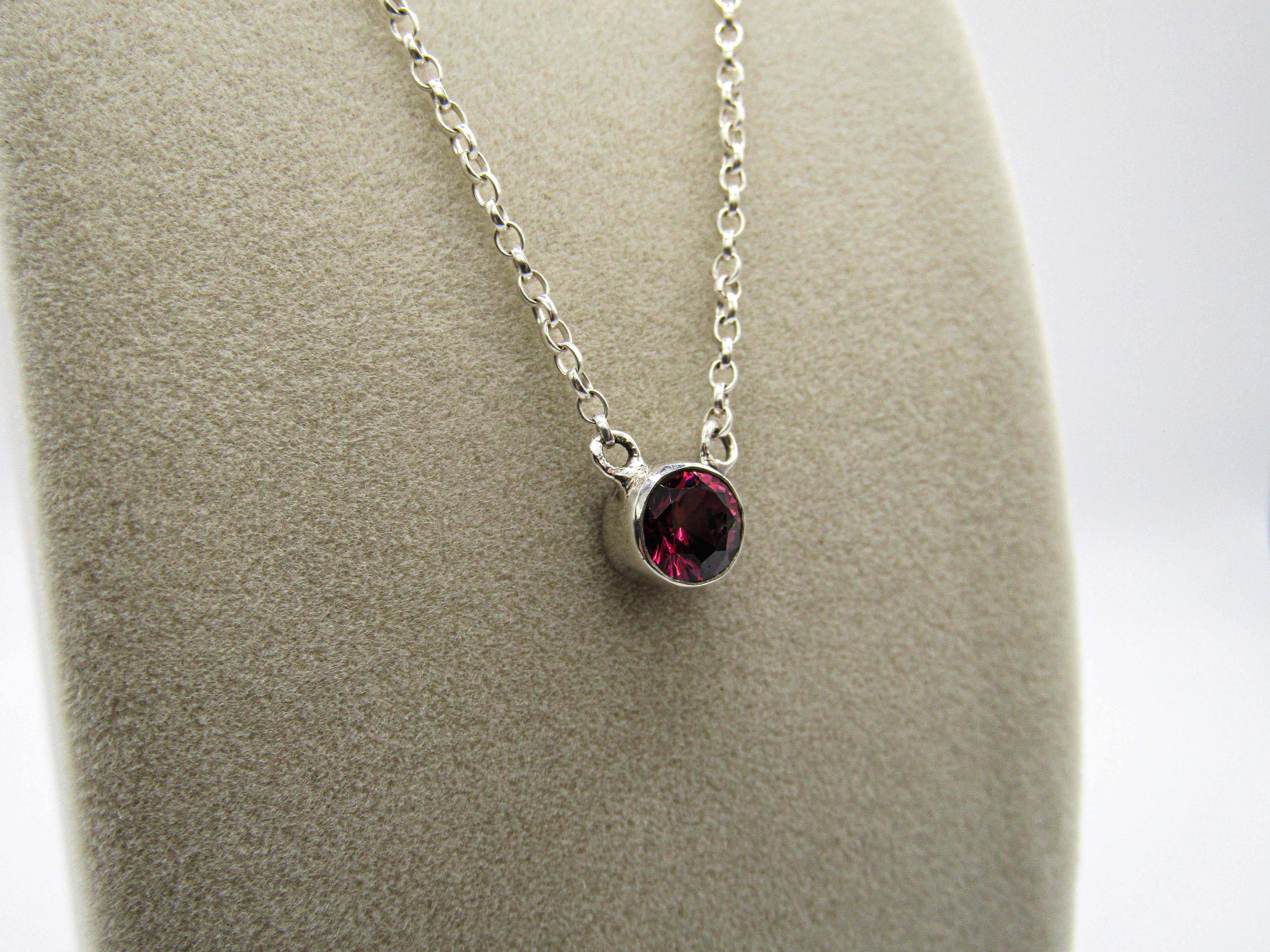 Silver necklace with a red gemstone pendant on a gray surface