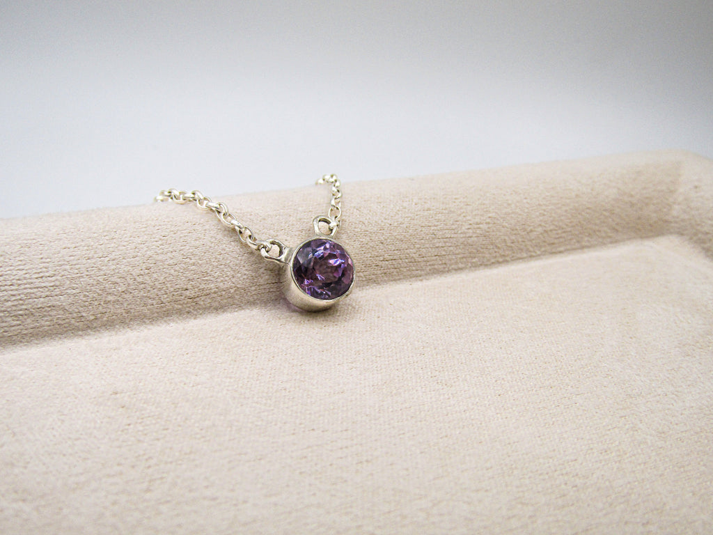 Necklace with a purple gemstone on a beige surface